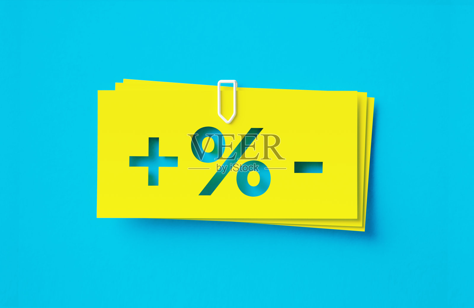 加减和百分比符号写的裁剪黄色胶粘笔记坐在蓝色背景照片摄影图片