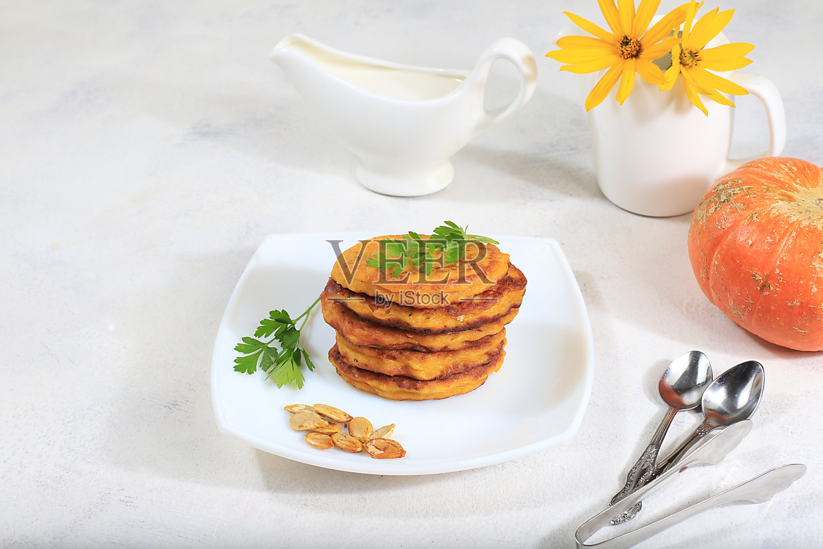 美味的俄罗斯煎饼配南瓜和一杯酸奶油放在明亮的桌子上,选择性的专注。传统的秋季减肥早餐照片摄影图片