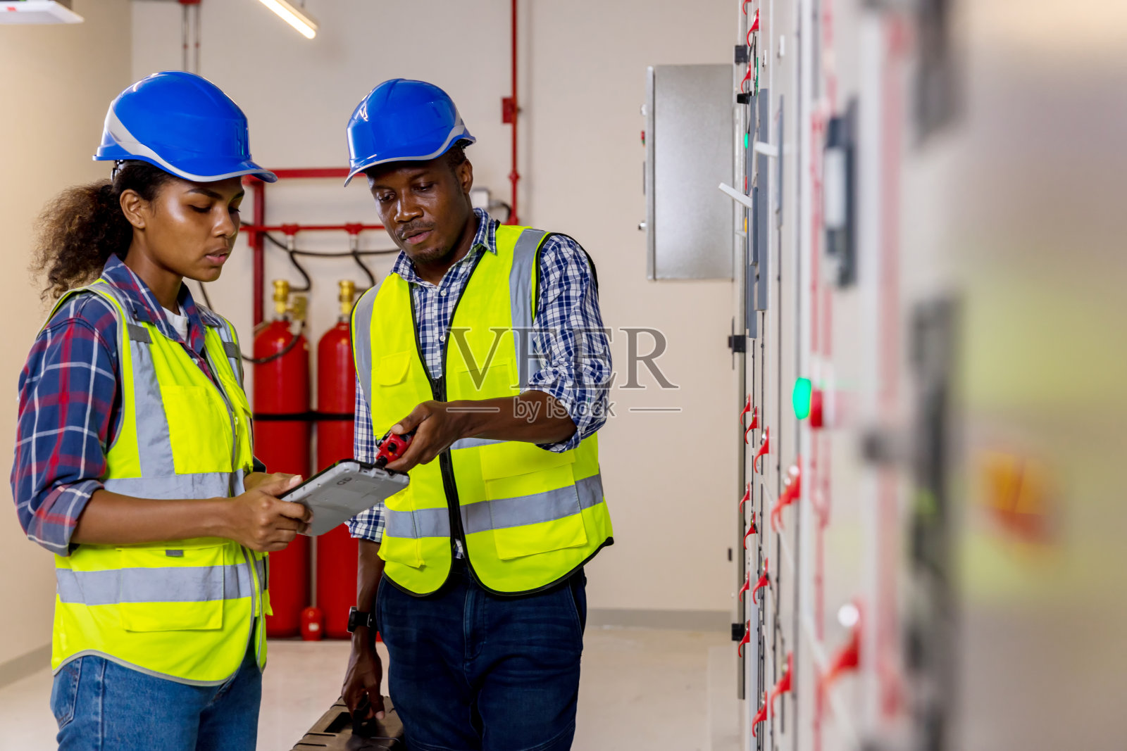 电气工程师在控制室工作。电气工程师在控制室检查配电柜照片摄影图片