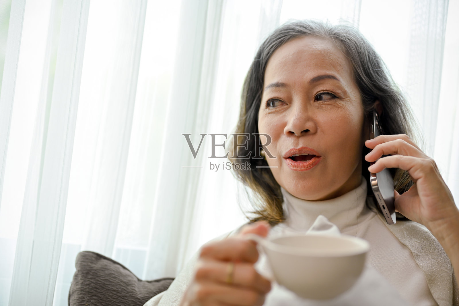 快乐的亚洲中年妇女与朋友在电话里愉快交谈,特写镜头照片摄影图片
