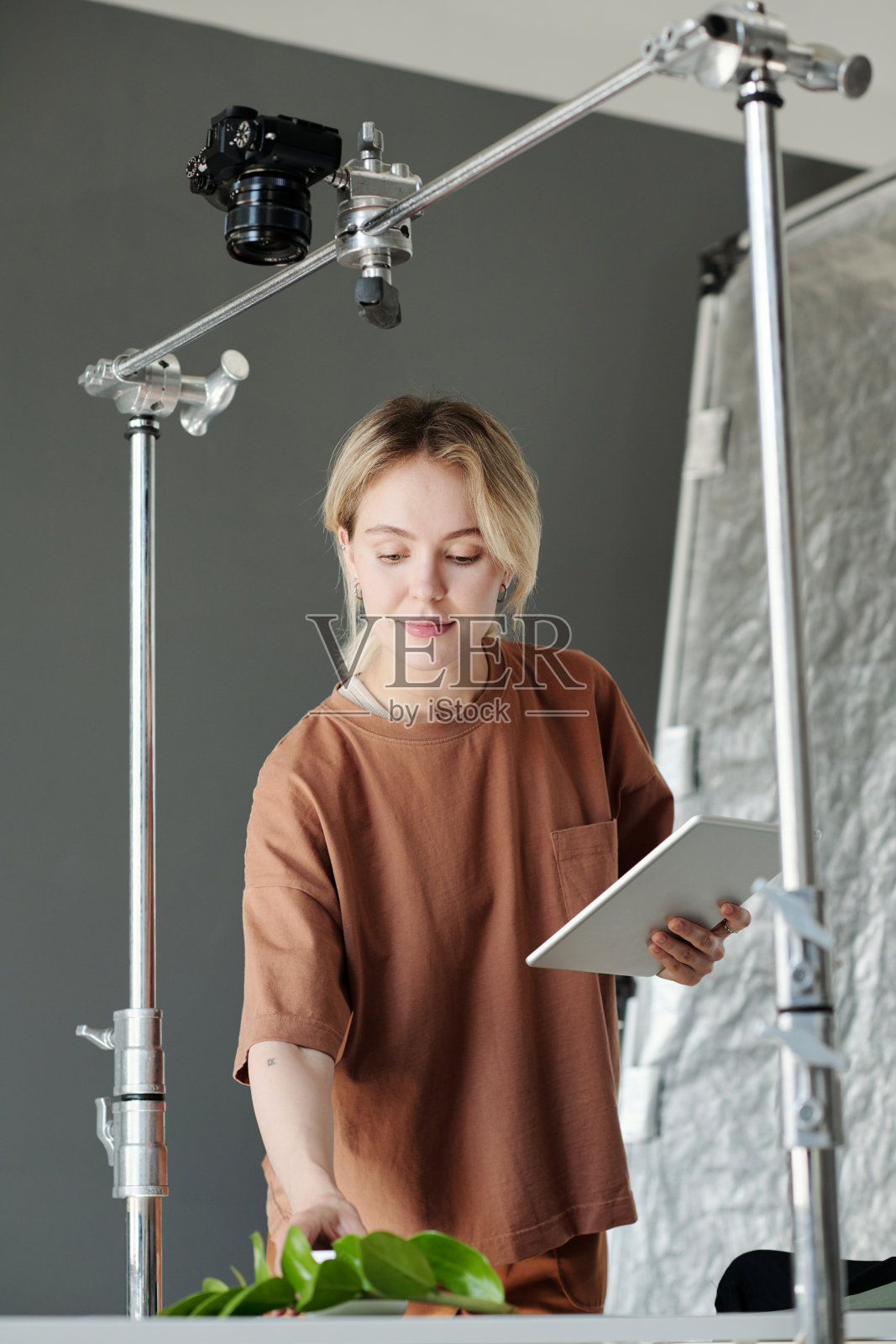 年轻微笑的女助理摄影师在桌子上创作构图照片摄影图片