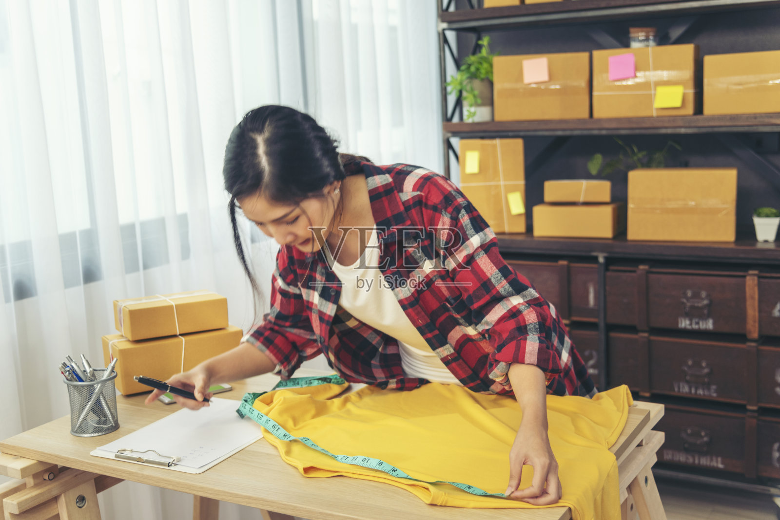 服装设计师妇女在桌子上测量服装设计包装盒。妇女检查货物的大小,质量到送货箱包装。企业家亚洲女性在家里的办公桌上开始小生意照片摄影图片
