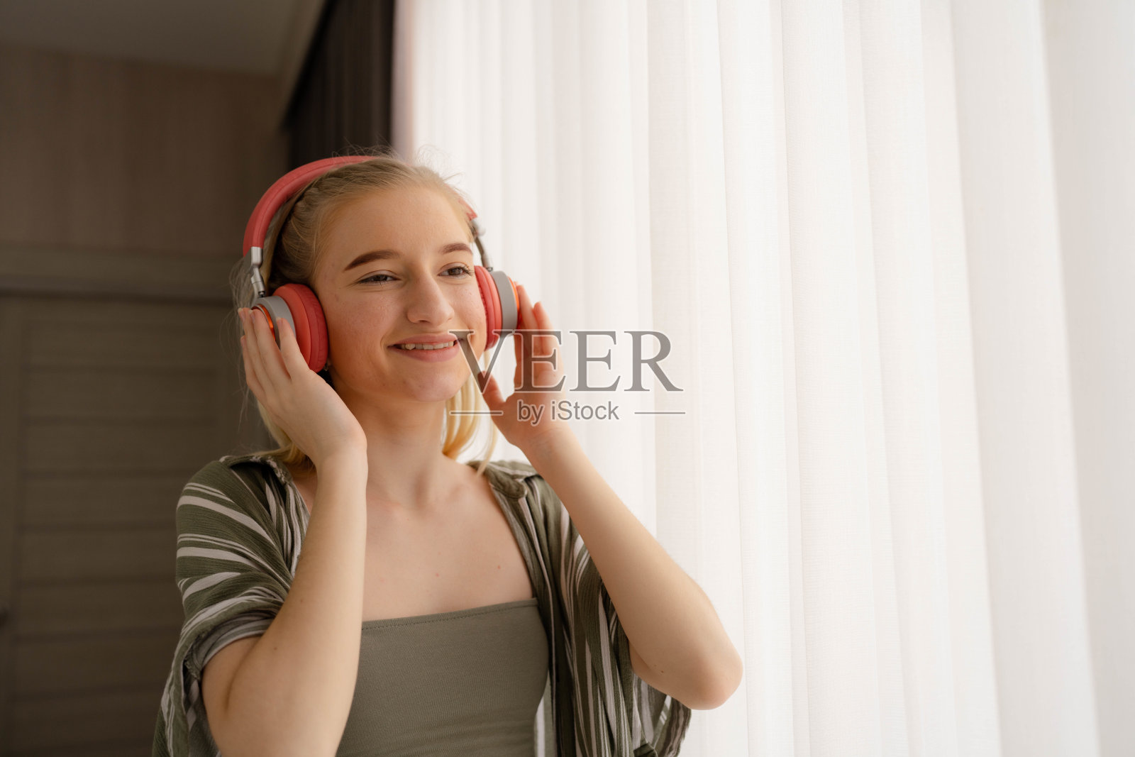 快乐的青少年女子听音乐通过互联网流与耳机。照片摄影图片