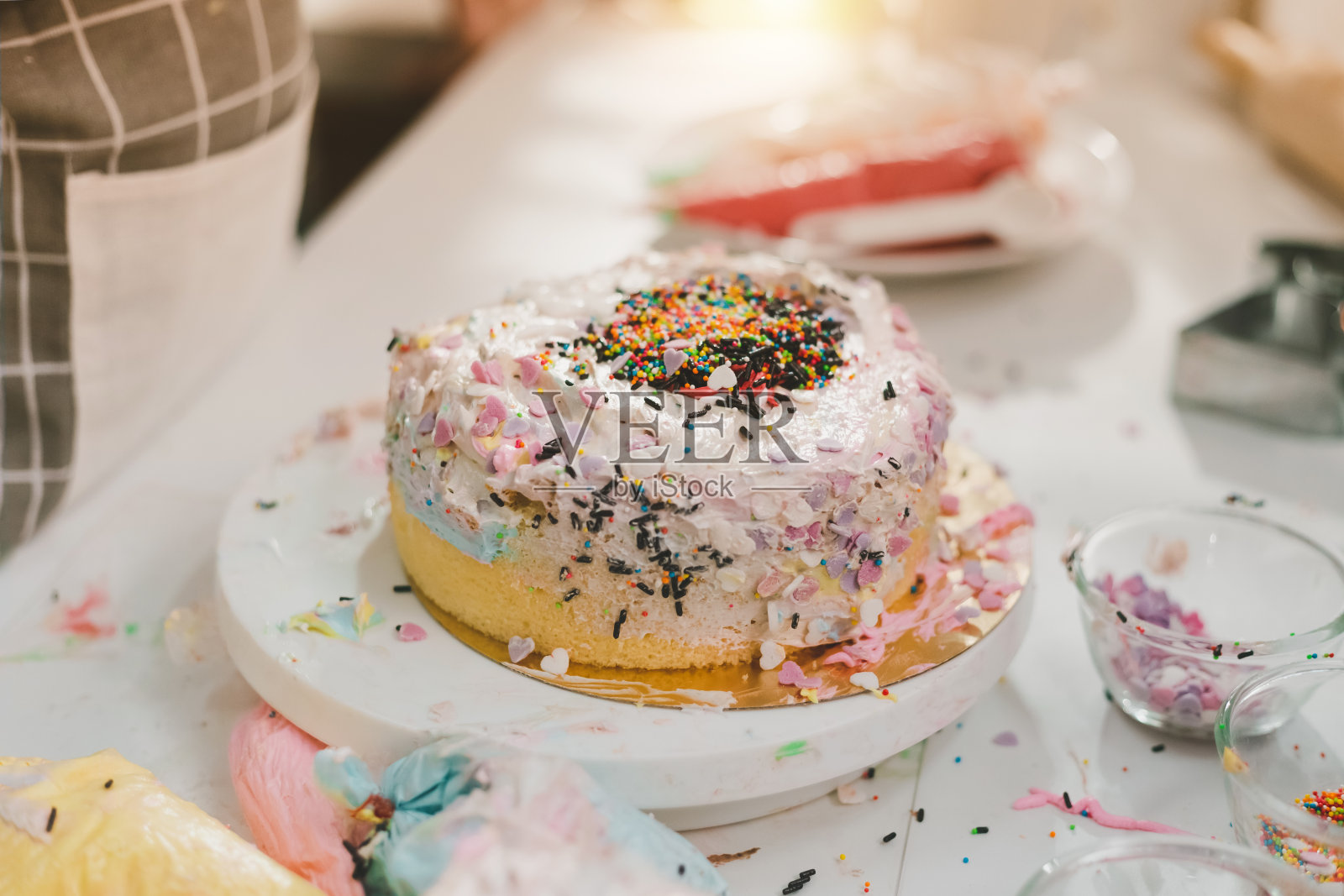 凌乱的厨房里摆着孩子们自制的生日蛋糕。厨房的配料在工作台上烘焙。凌乱的桌子上堆满了糕点和食材。照片摄影图片