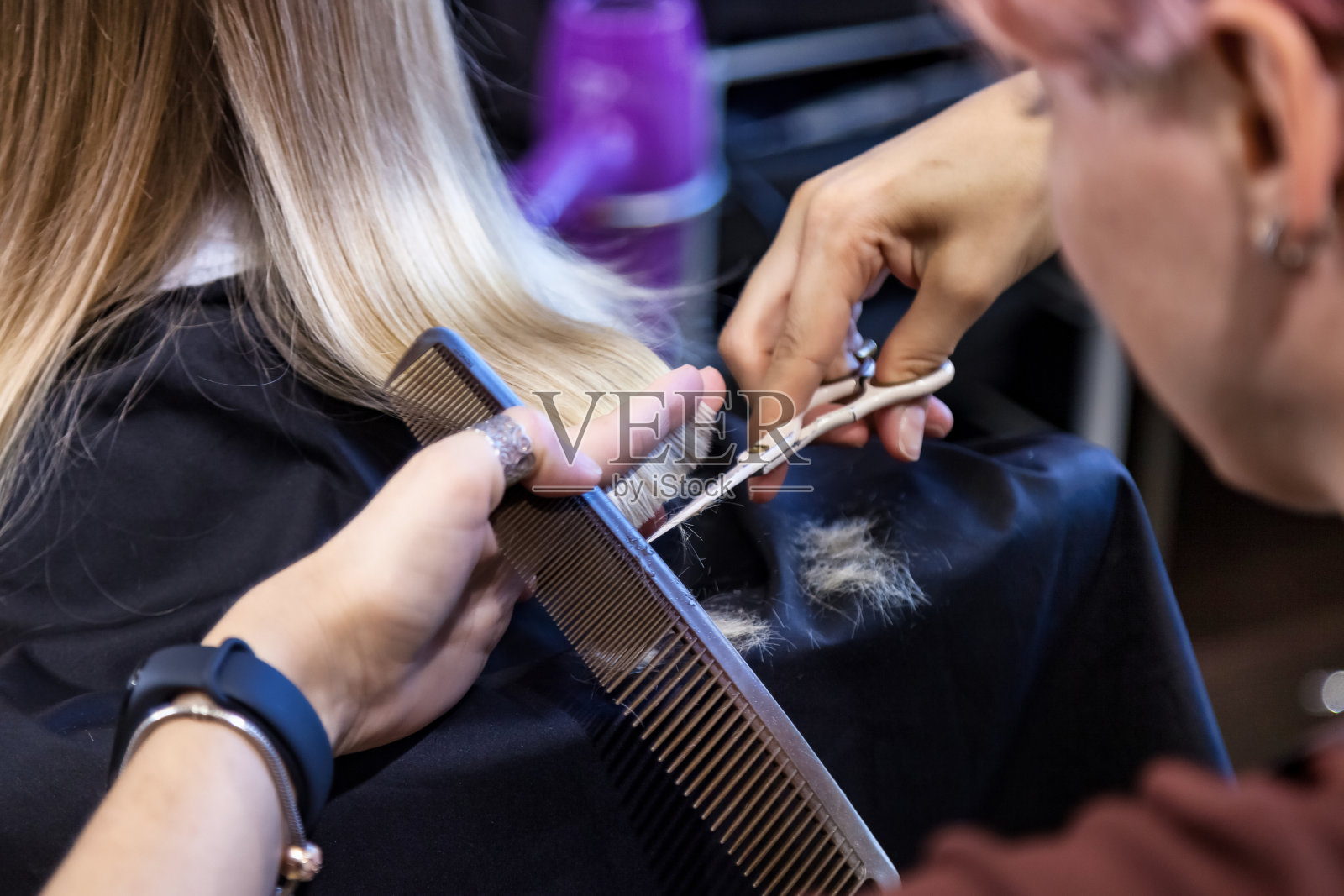 美发沙龙,近理发师妇女为可爱的金发小女孩在现代理发店时髦漂亮的发型。理发师在理发店为婴儿做发型。发型、美容概念照片摄影图片