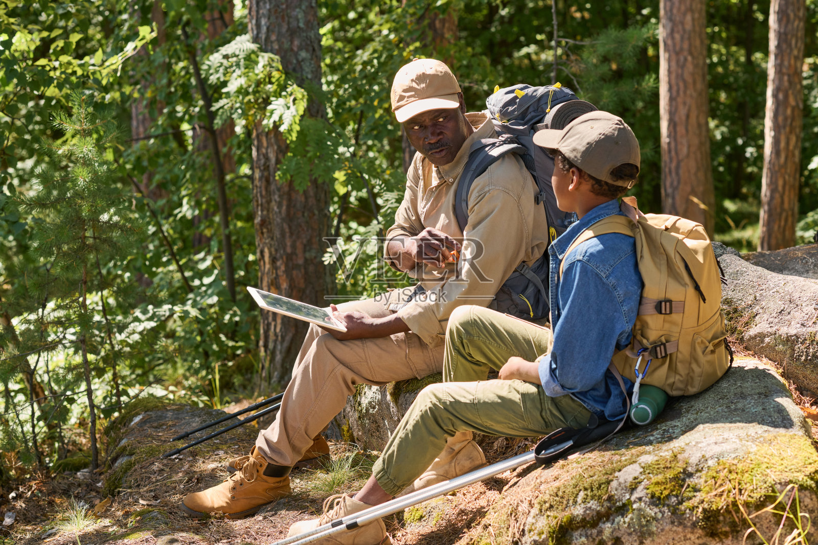 成熟的非裔美国人拿着平板电脑和背包和他的孙子说话照片摄影图片