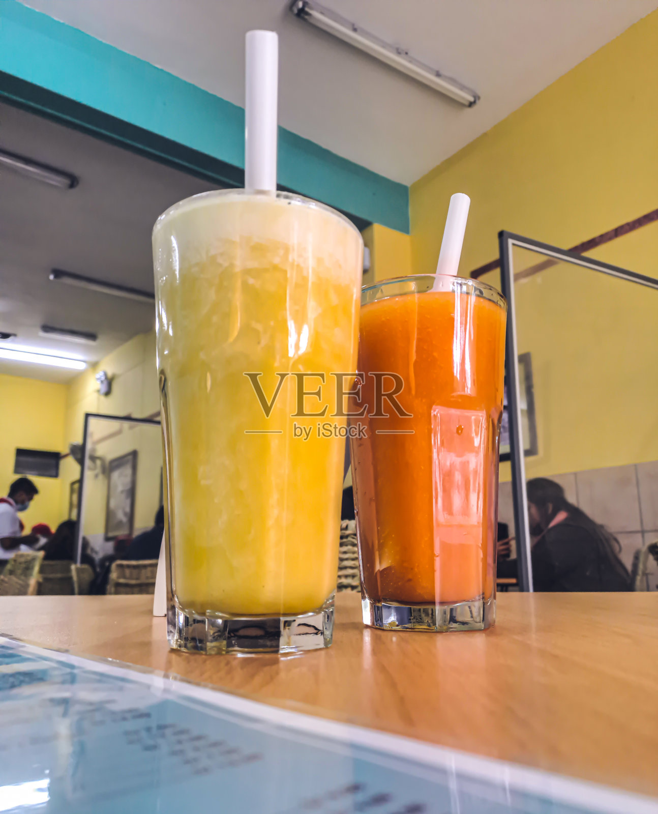 菠萝和木瓜汁装在两大杯里,每杯都加了稻草。照片摄影图片