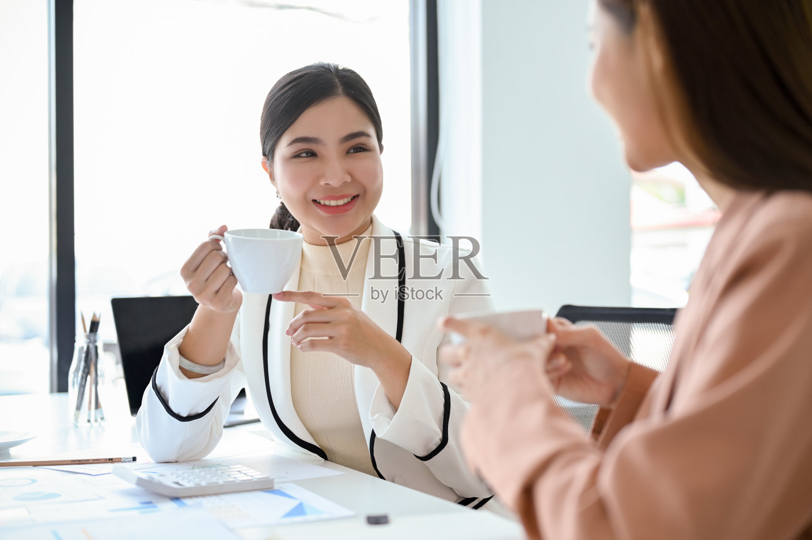 年轻漂亮的亚洲女老板与助手愉快交谈照片摄影图片