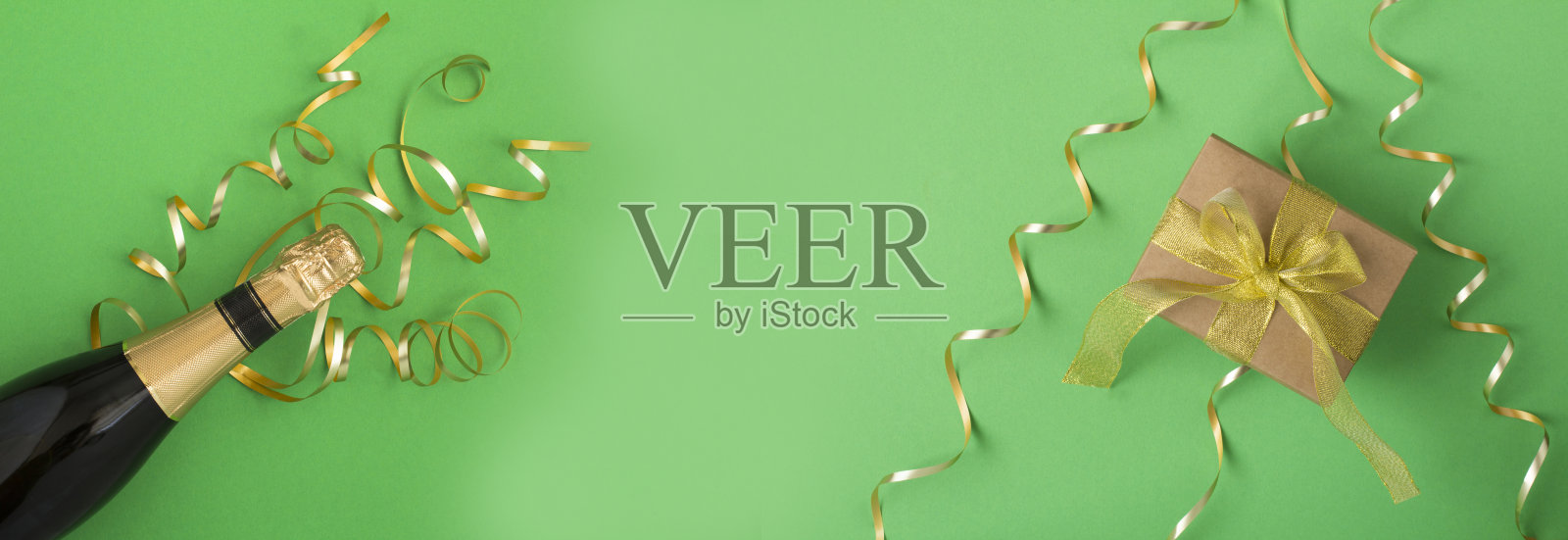 圣诞节的旗帜。绿色背景上的圣诞礼物和一瓶香槟。副本的空间。前视图。照片摄影图片