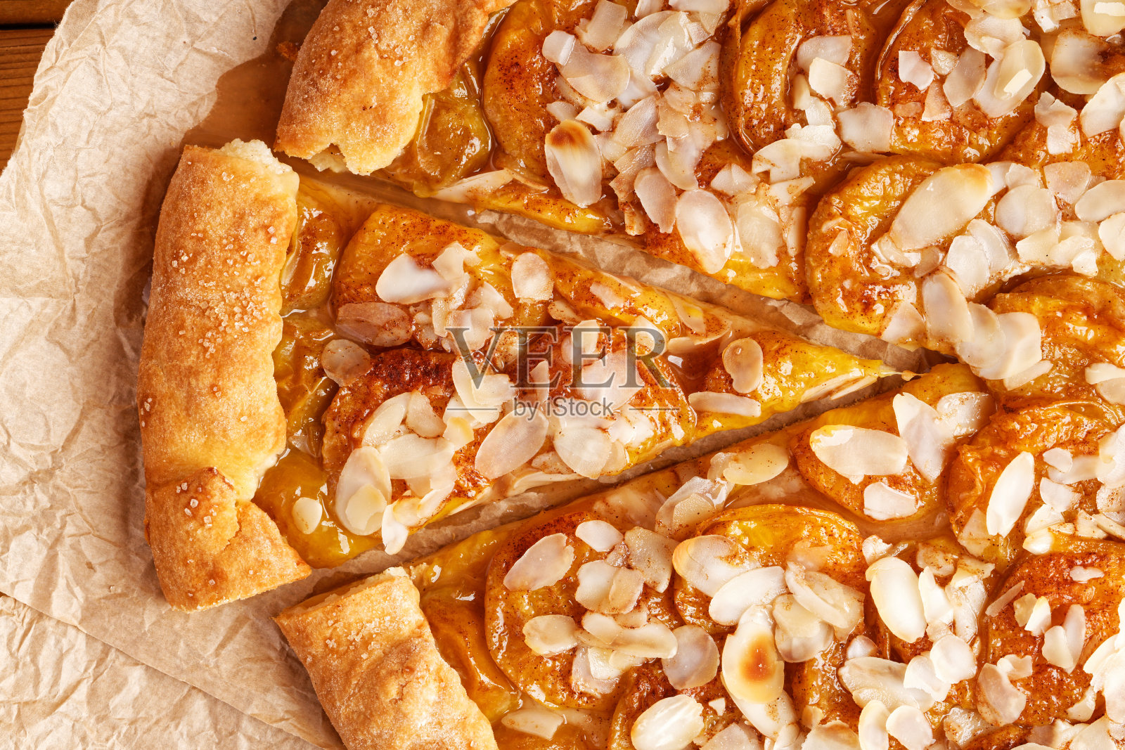 自制派的特写,李子和杏仁花瓣放在羊皮纸上。前视图。照片摄影图片