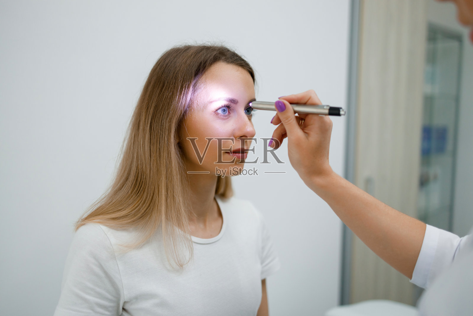 神经科医生用手电筒检查瞳孔对光的反应照片摄影图片