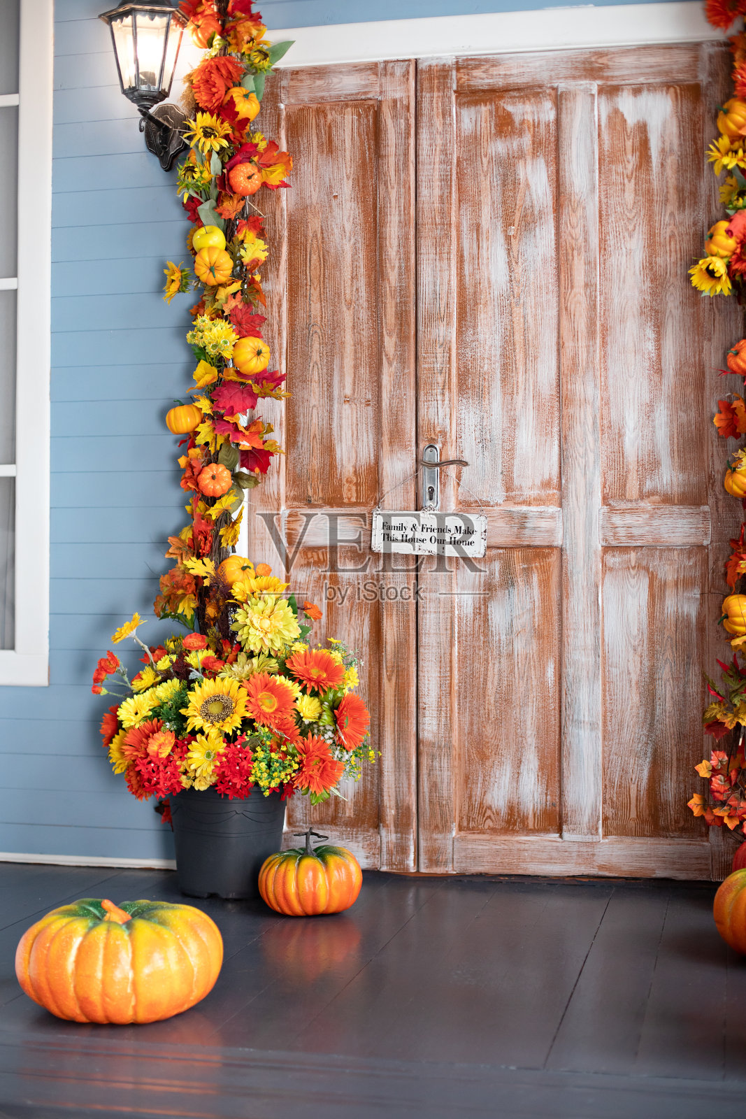 万圣节的构图设计家与黄色的落叶和花朵。房屋入口楼梯装饰为秋天的节日,秋天的花朵和南瓜。舒适的木制门廊的房子与南瓜在秋天照片摄影图片