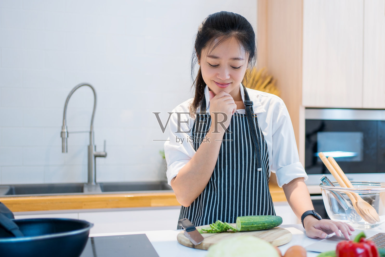 一个美丽的亚洲女人的肖像站在棕色的木制厨房里。包括各种水果和蔬菜为家庭。照片摄影图片