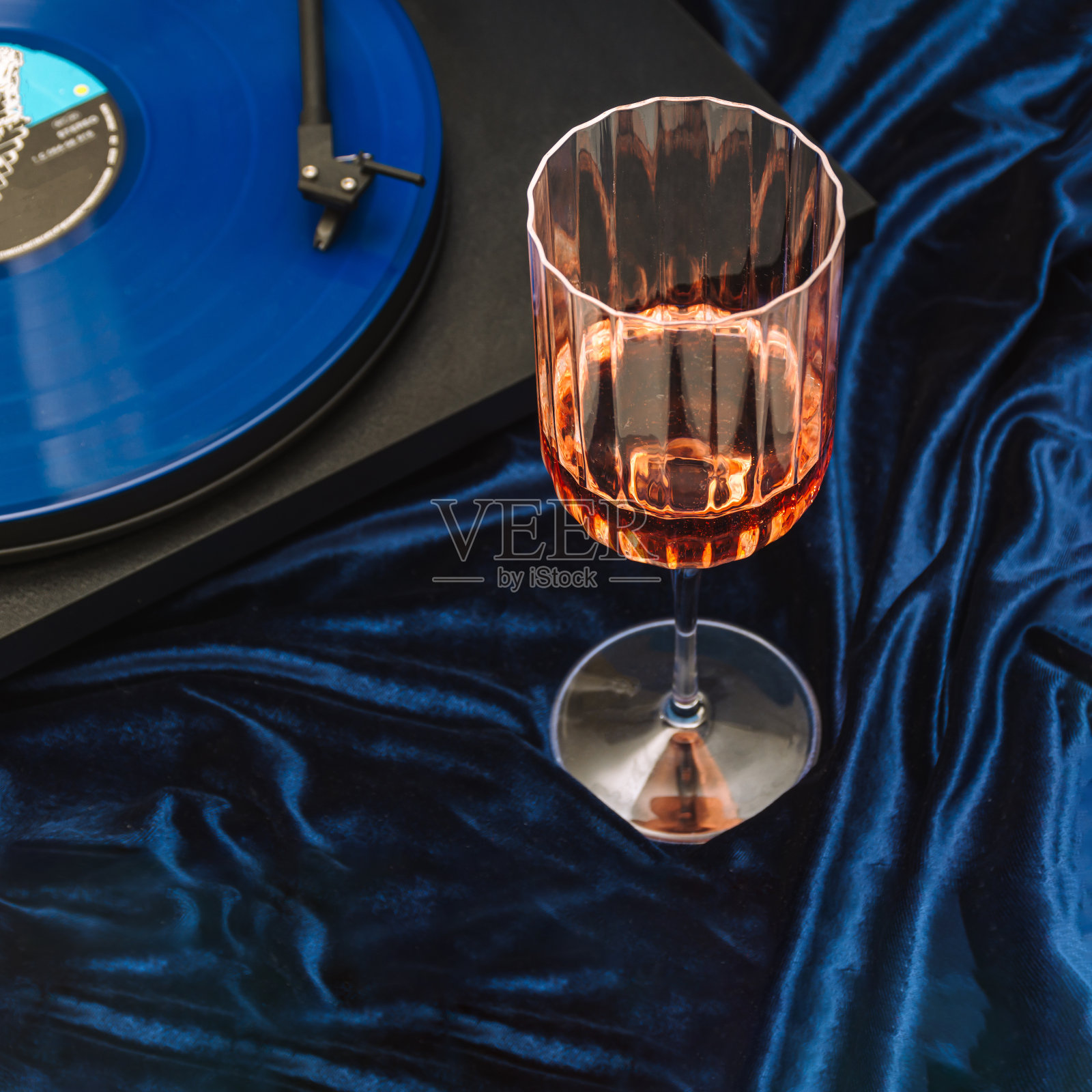 葡萄酒杯与玫瑰和乙烯基lp在转盘组成金属蓝色背景。颓废的一方设置。照片摄影图片