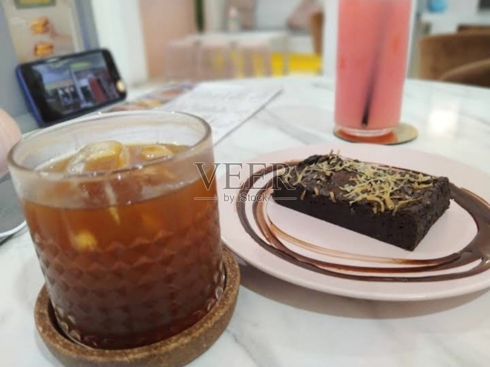 这家印尼咖啡馆的简单午餐菜单包括一杯科勒克,一杯草莓冰,一盘黑面包,上面有奶酪。照片摄影图片