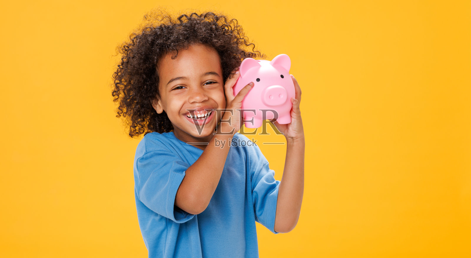 快乐的民族男孩在存钱罐里存钱照片摄影图片