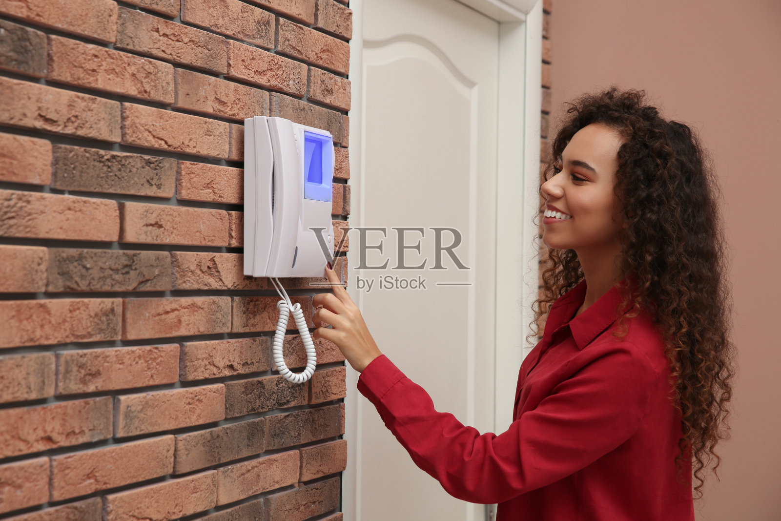 年轻的非裔美国妇女在室内按对讲机面板上的按钮照片摄影图片