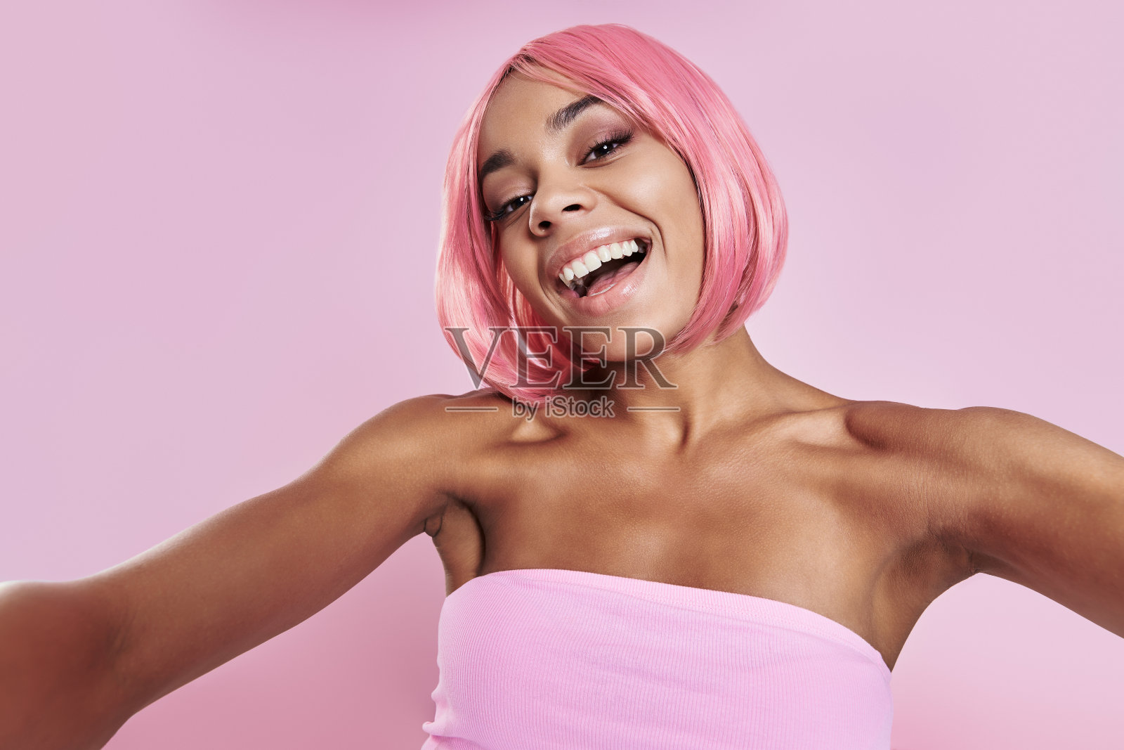 快乐的年轻非洲妇女粉色头发在粉色背景下自拍照片摄影图片
