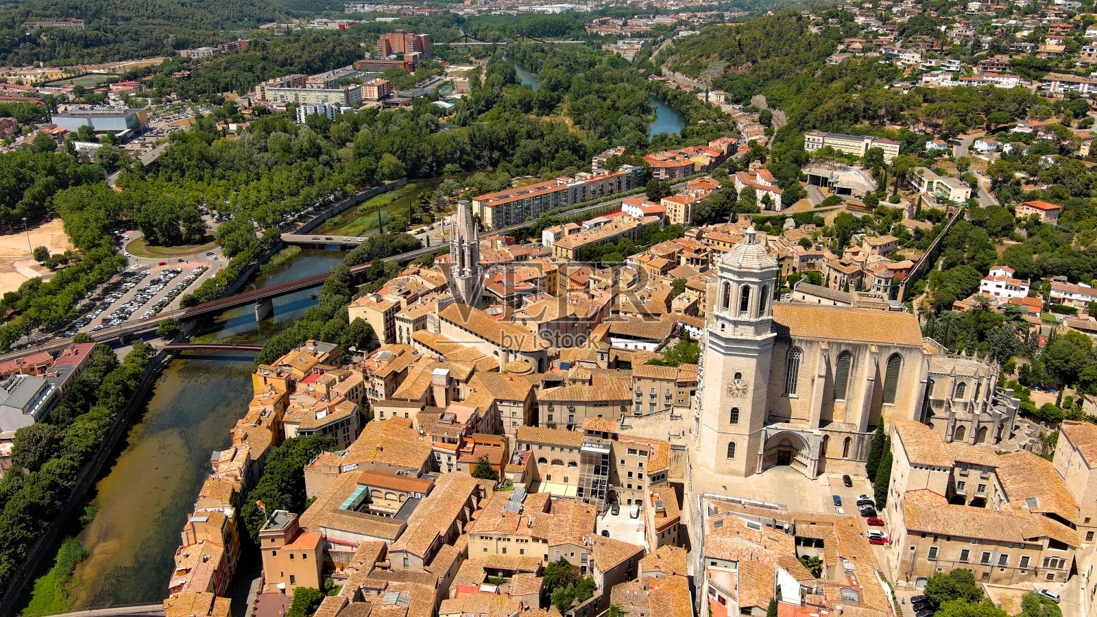 西班牙加泰罗尼亚,鸟瞰赫罗纳、圣菲利乌教堂和圣玛丽大教堂在一个美丽的夏日。黄色和橙色的房屋倒映在奥尼亚河的水中照片摄影图片