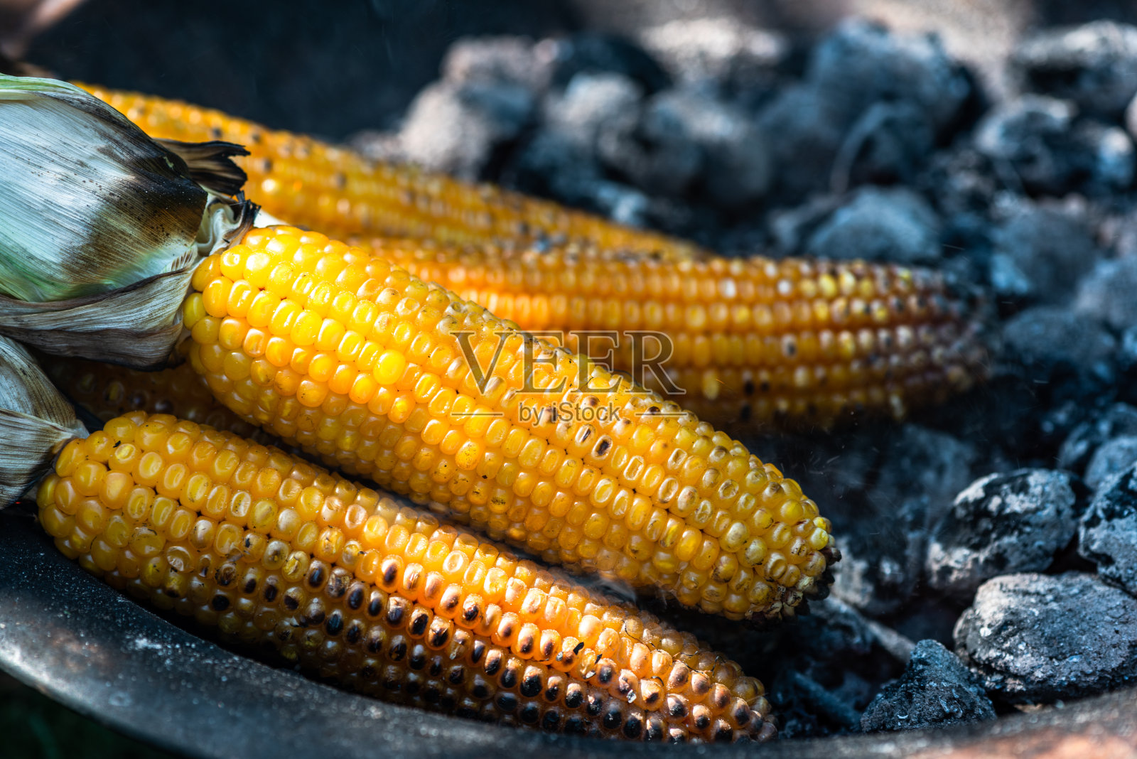 烤玉米棒在热的烧烤煤,近距离观看,秋季野餐食品照片摄影图片