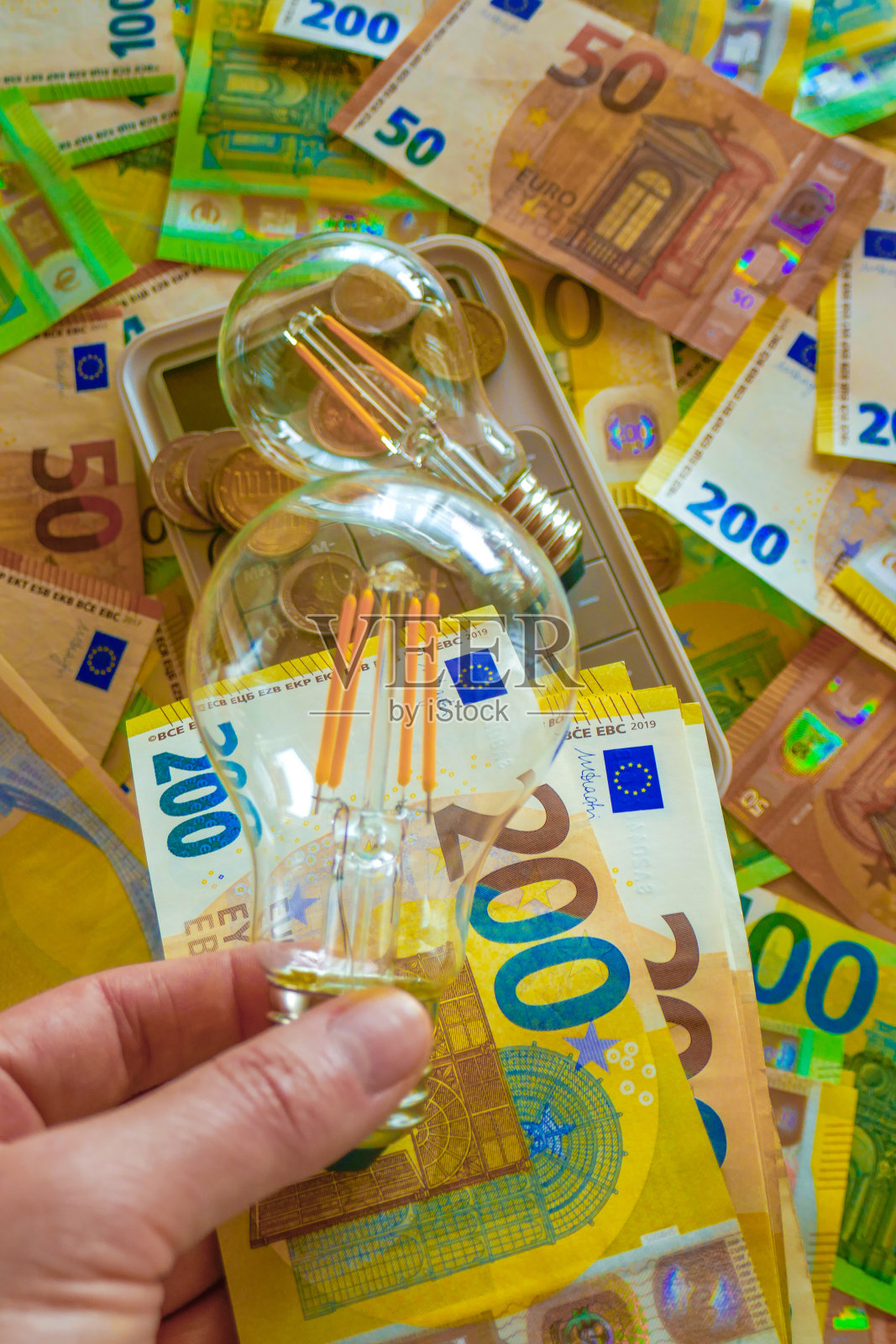 电力成本。手持电灯泡的欧元纸币背景。电力价格上涨。支付电费。公用事业服务的费用。欧洲国家的能源生产危机。照片摄影图片