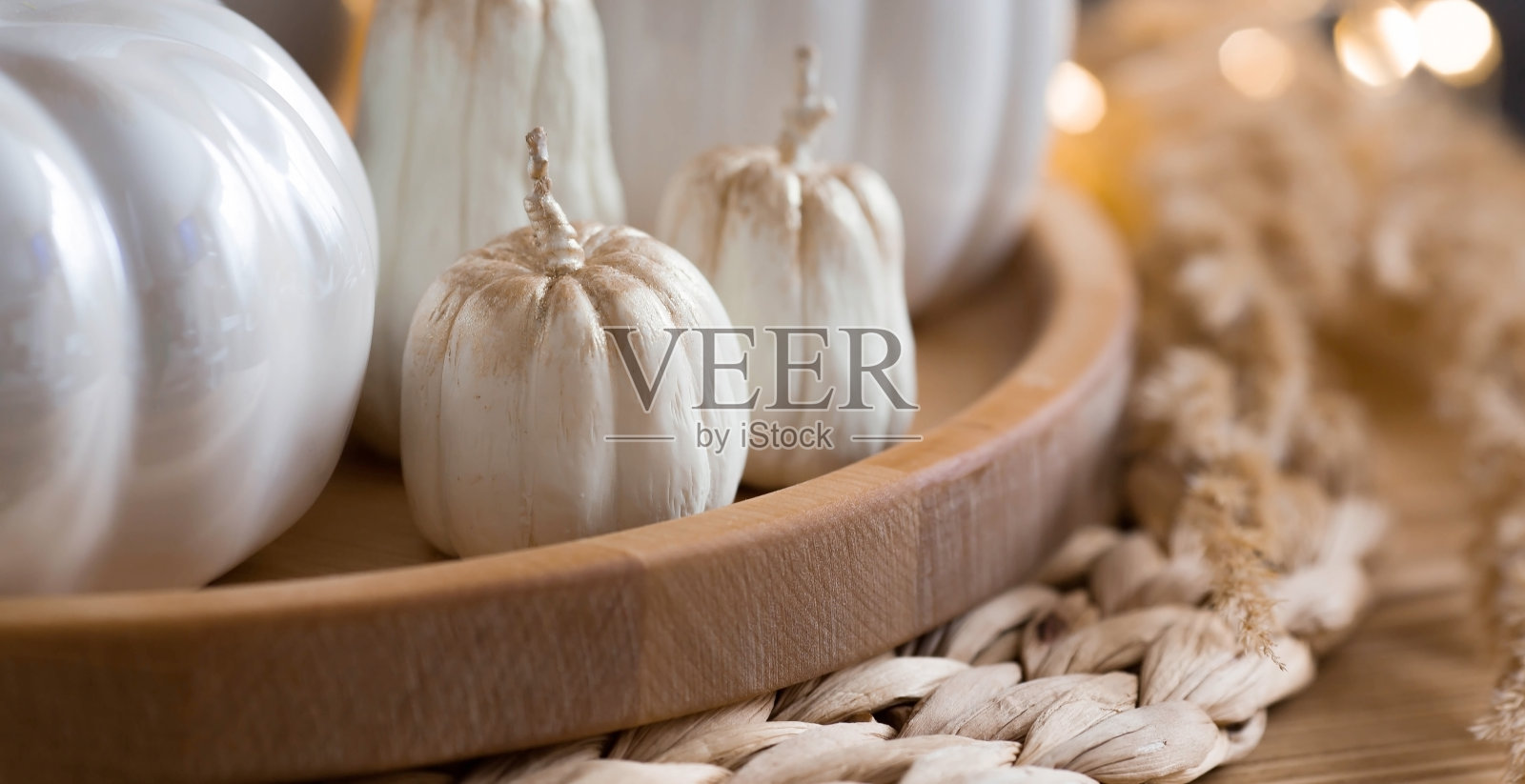 静物。白色陶瓷南瓜,潘帕斯草,南瓜形状的蜡烛放在客厅室内的家庭咖啡桌上。装饰的细节。舒适的秋天的概念。照片摄影图片