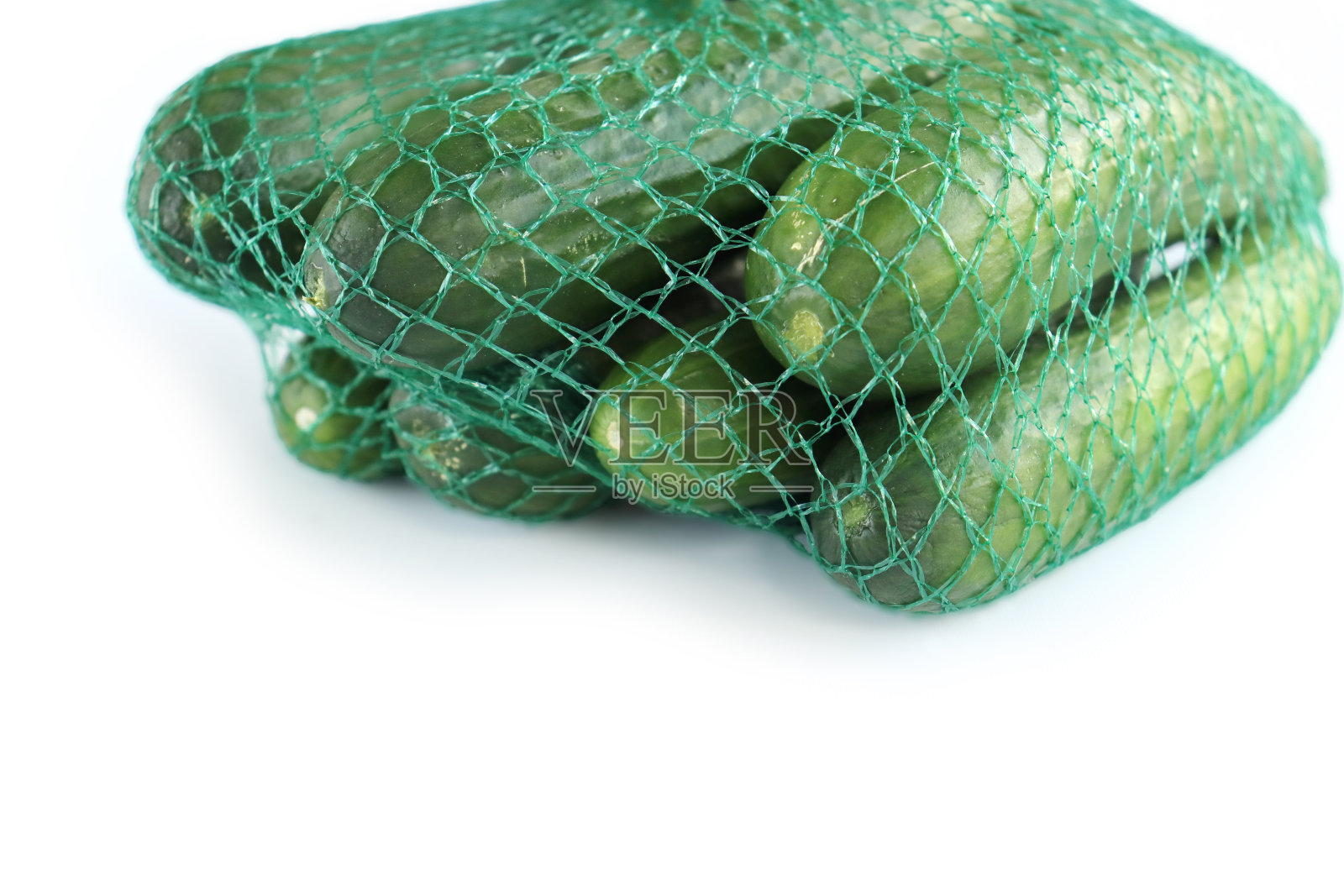 绿色的塑料网袋里装着一堆绿色的黄瓜。孤立在白色背景上。空间的文本。副本的空间。前视图。侧视图。特写镜头照片摄影图片