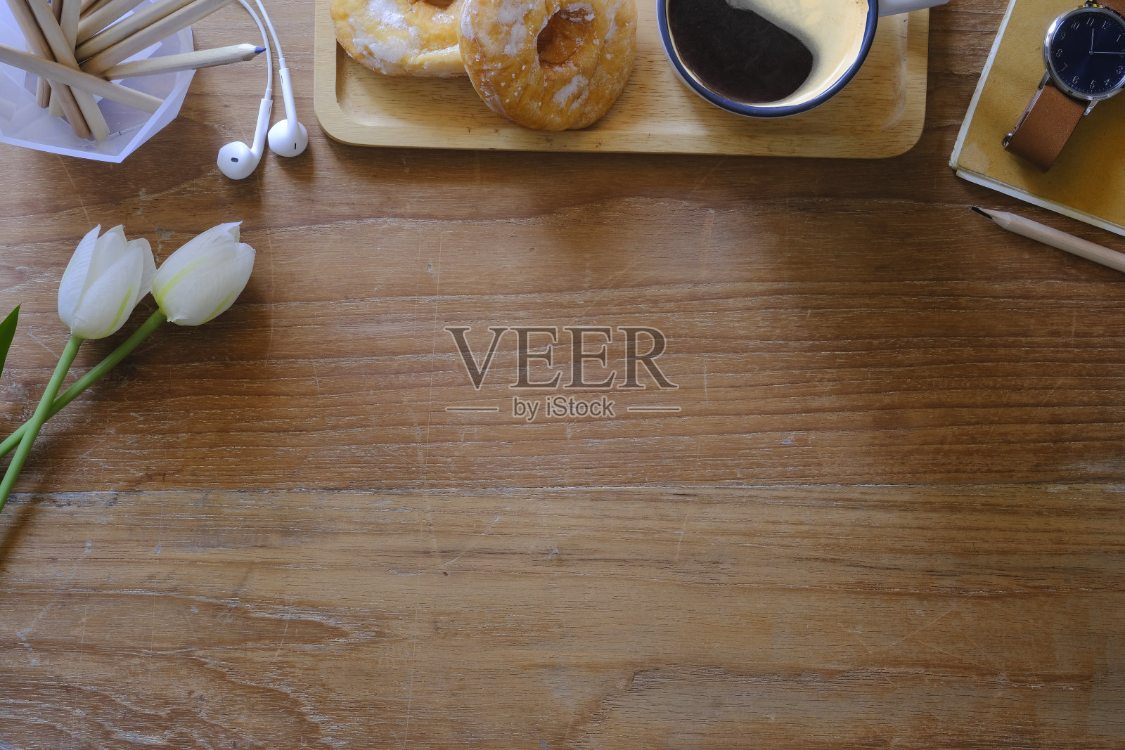 平放咖啡杯,白色郁金香和耳机在木桌上。带有复制空间的俯视图。照片摄影图片