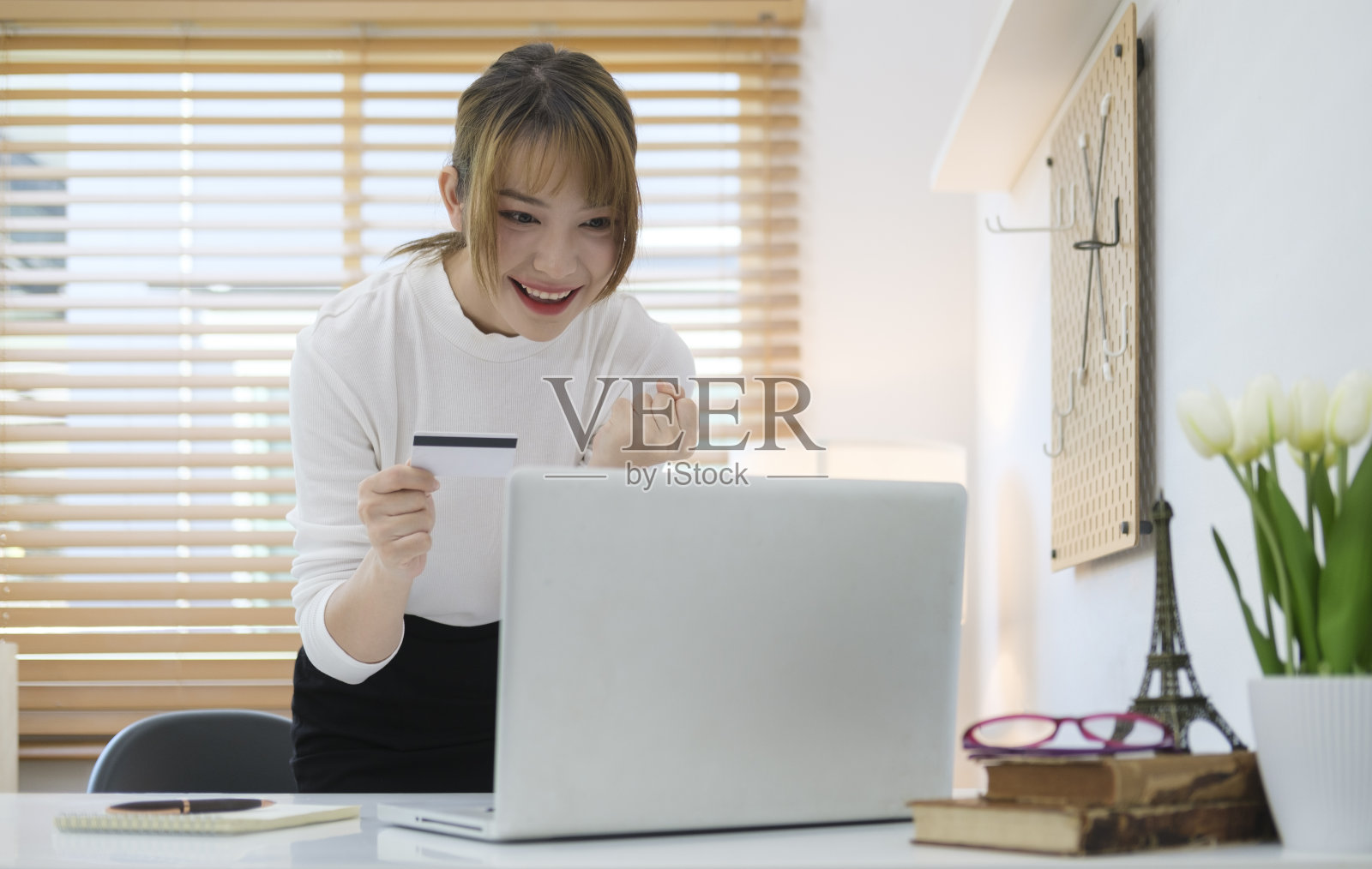 快乐的年轻亚洲妇女持有信用卡和使用笔记本电脑进行网上银行。照片摄影图片