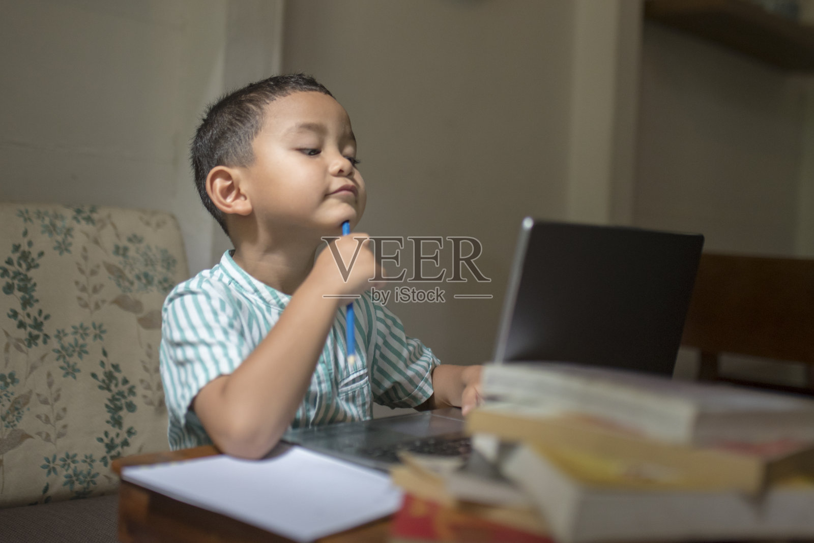 在笔记本电脑前表情困惑的亚洲儿童照片摄影图片