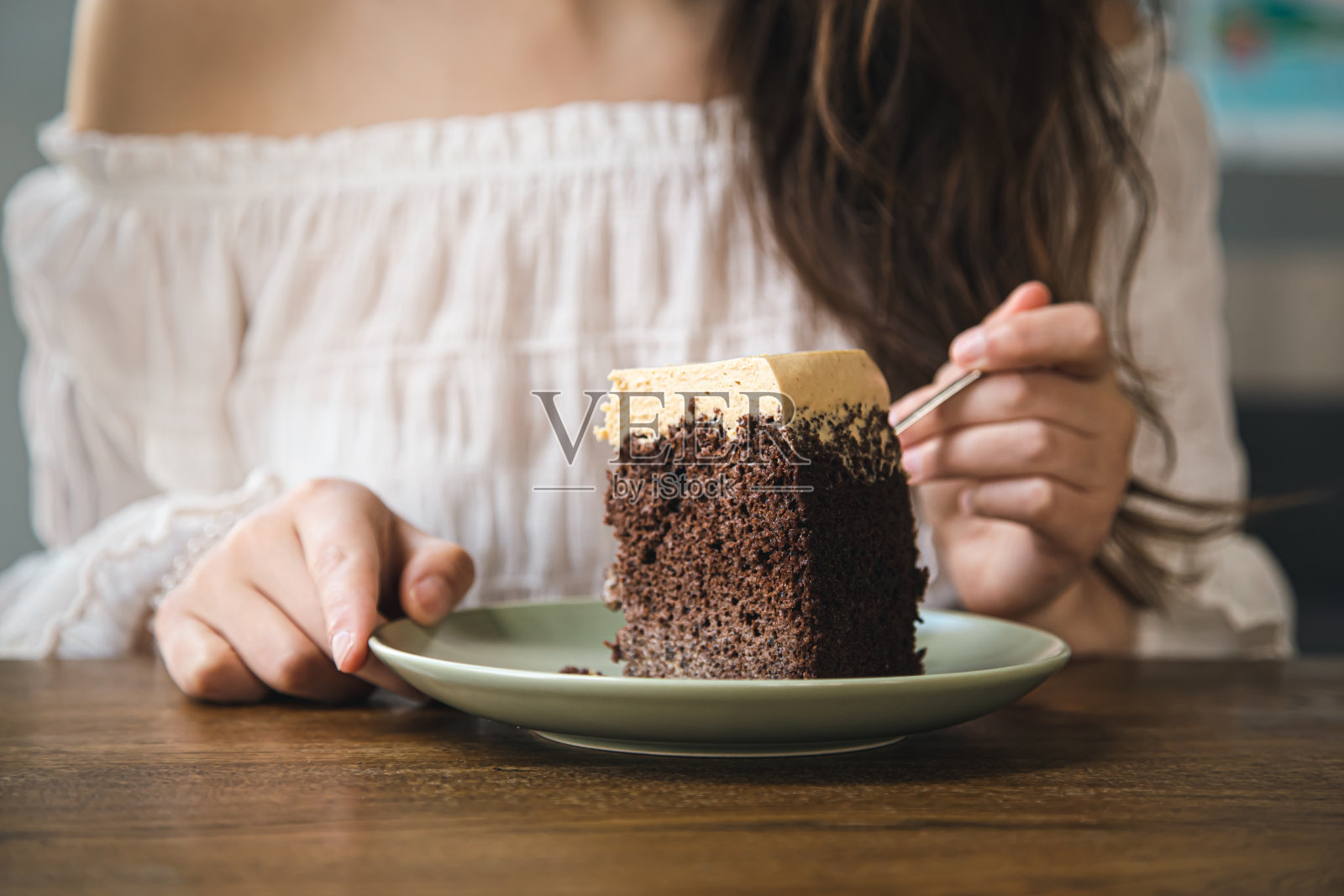 一个女人在吃一块巧克力蛋糕,特写。照片摄影图片
