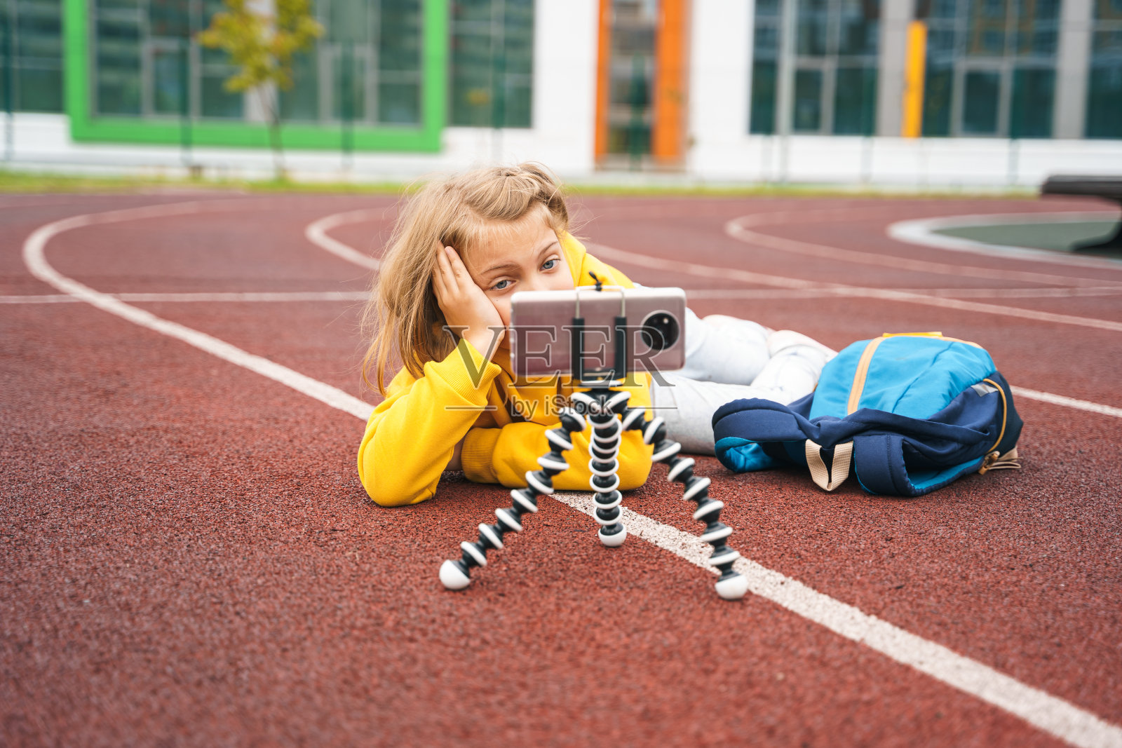 十几岁的女孩穿着卫衣,带着手机,书包在校园里。博客为博客录制视频在体育playgroumd体育场。和妈妈、朋友、同学聊天。在大学里休息。初等教育照片摄影图片