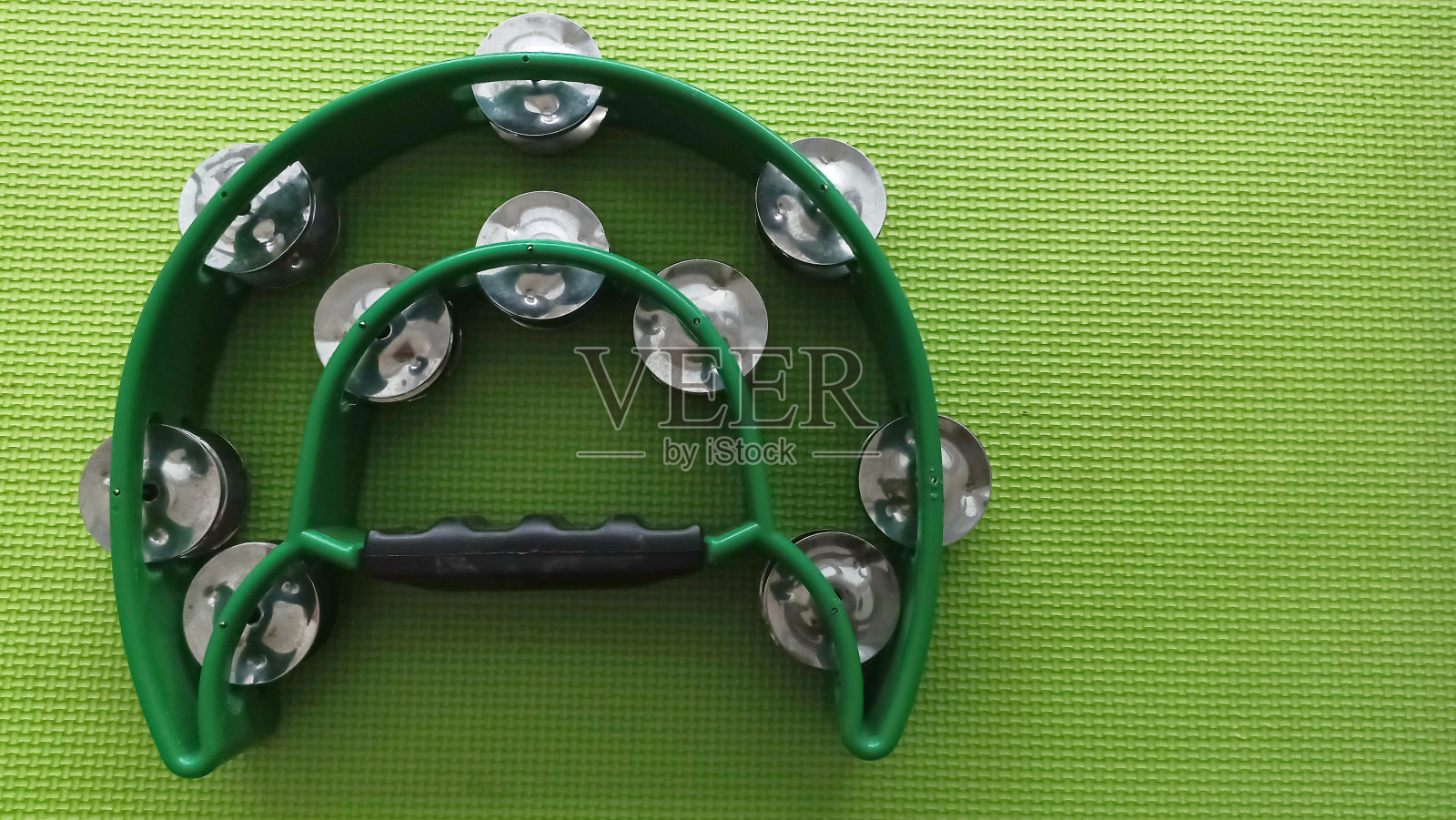 双排把手铃鼓孤立在绿色背景。叮当手打击乐。照片摄影图片