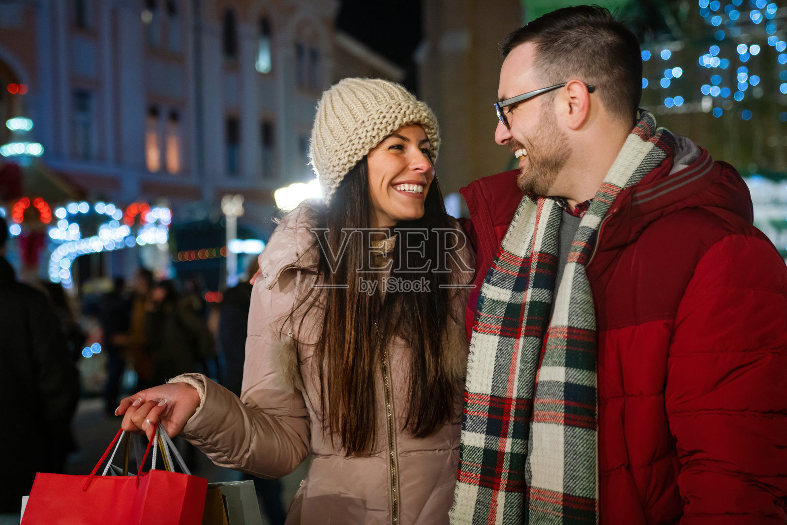 一对快乐的夫妇站在装饰华丽的街道上购物。销售人的概念照片摄影图片
