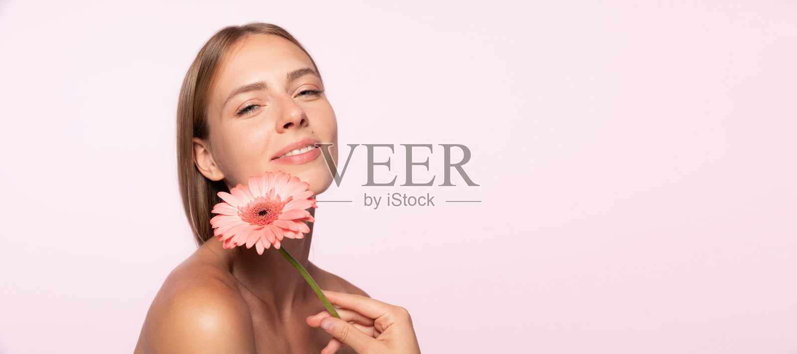 美丽的年轻女孩,有光泽的金发拿着花孤立在白色的背景。形状和线条,化妆品,自然美照片摄影图片