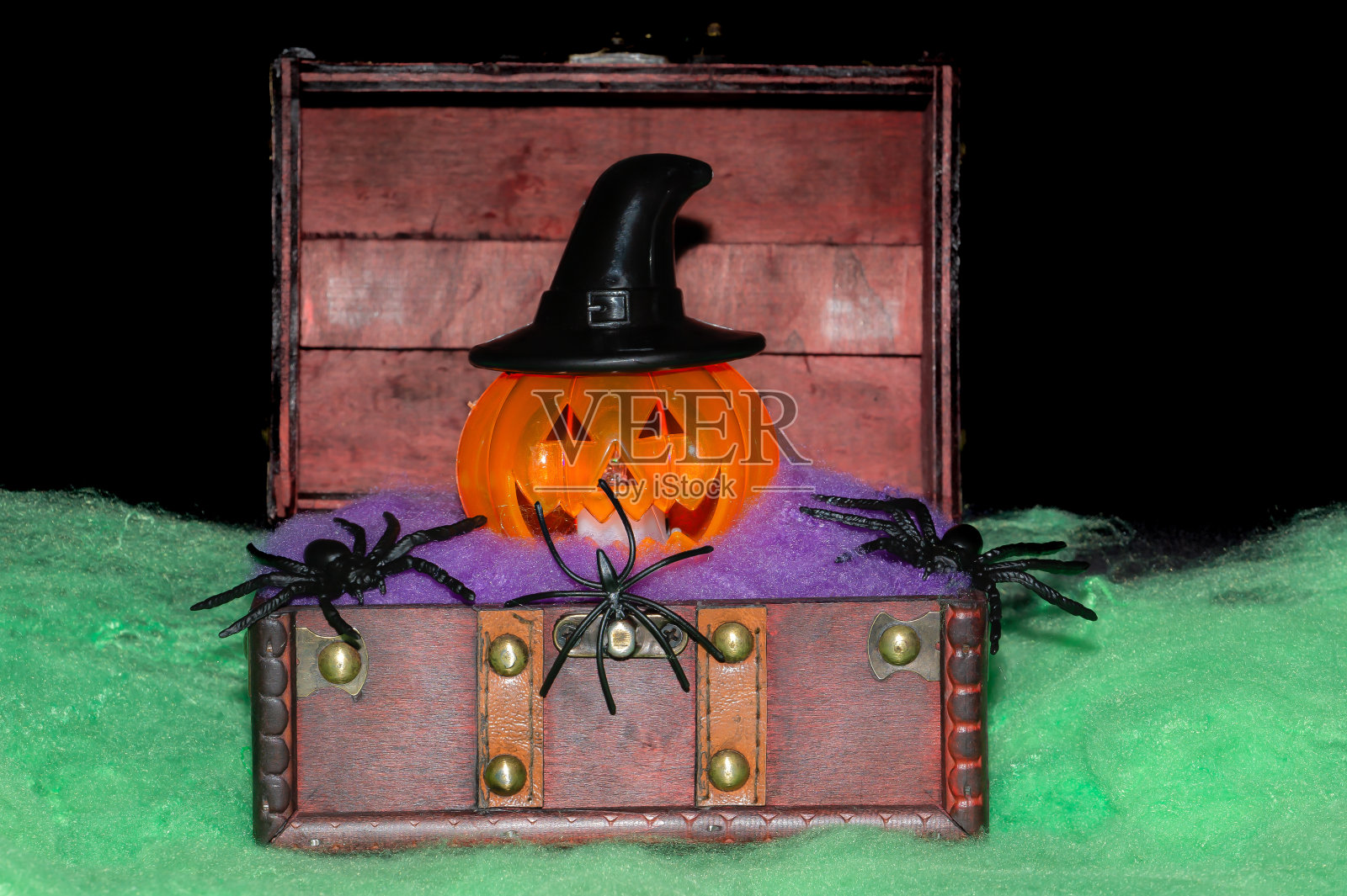 万圣节南瓜,里面有一个木制的箱子,里面有一顶黑色的帽子,周围有蜘蛛。假期,万圣节。亡灵节照片摄影图片