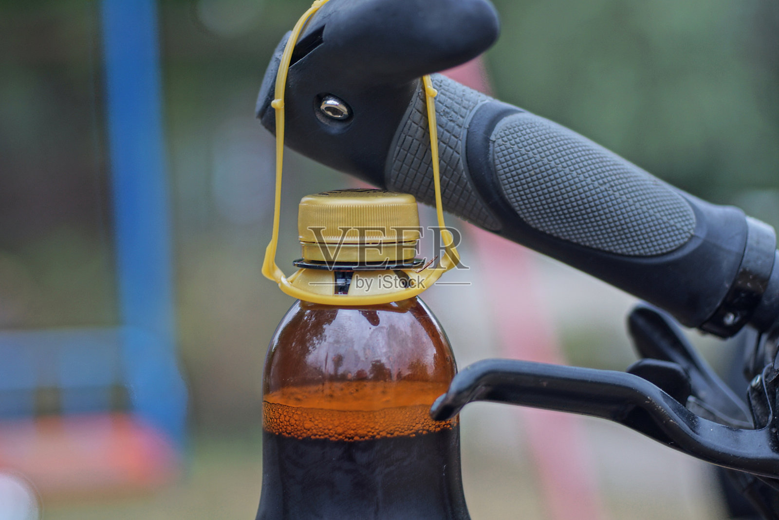 一个装着饮料的棕色塑料瓶挂在一辆自行车的黑色车把上照片摄影图片