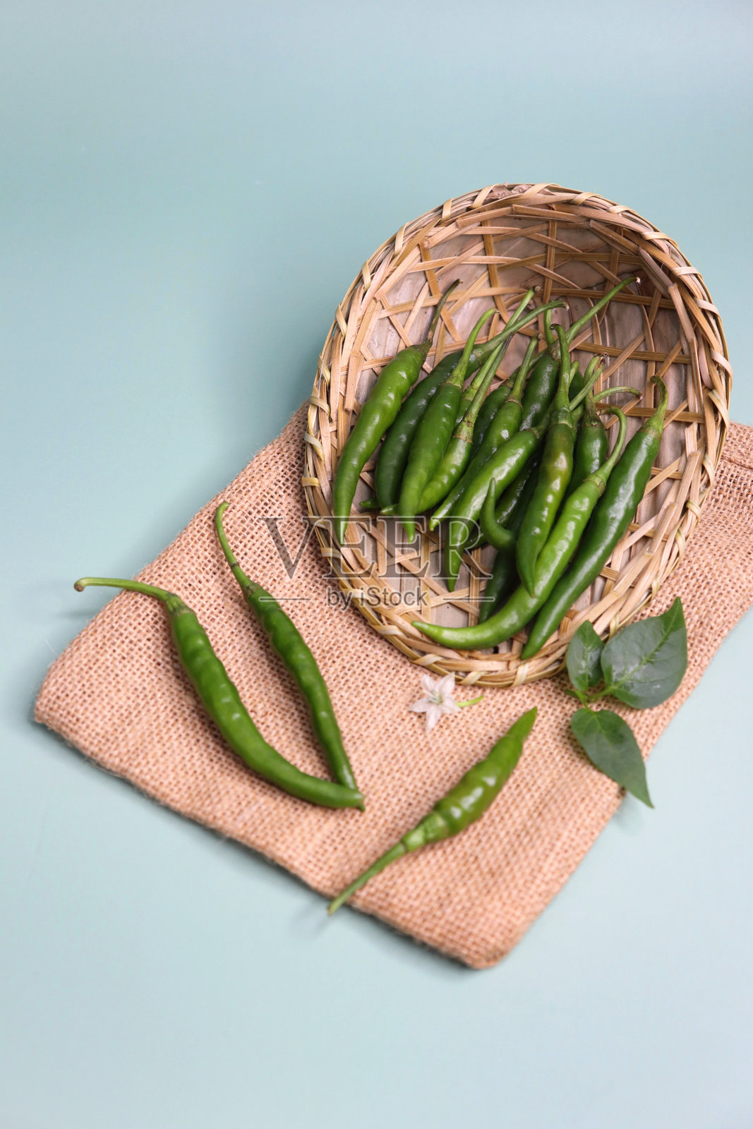 种植新鲜的有机绿辣椒。新鲜收获的健康辛辣的辣椒放在绿色背景的篮子里。副本的空间。照片摄影图片