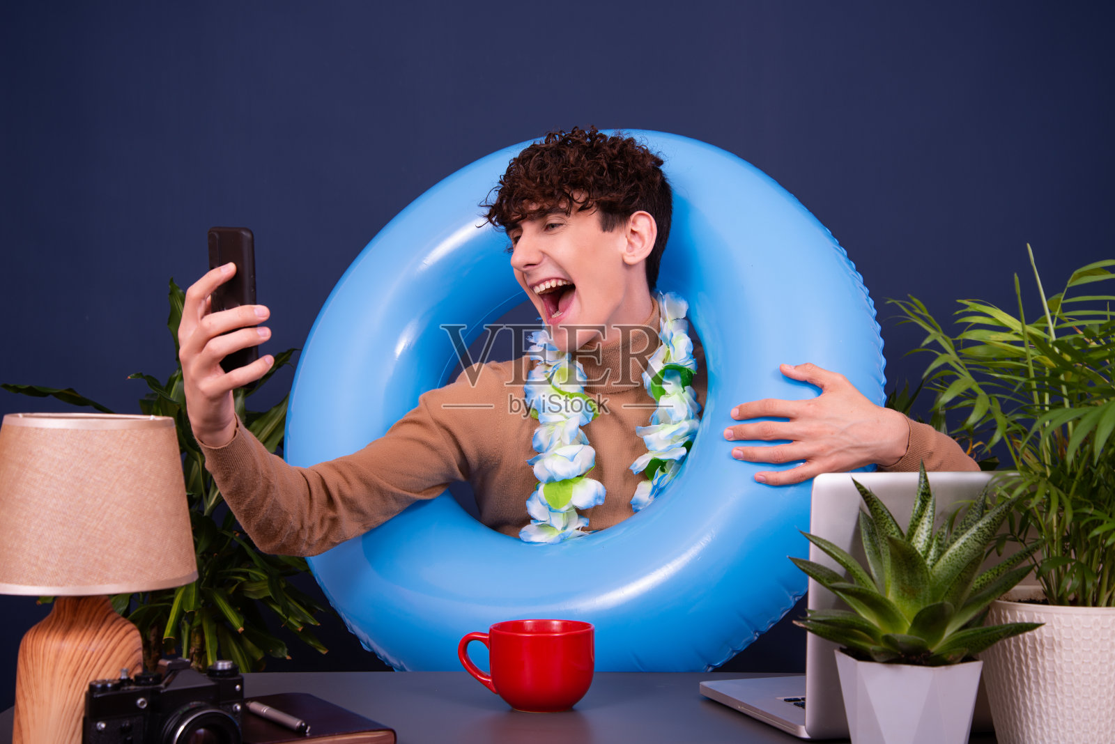 一个年轻有魅力的家伙在办公室工作,梦想着度假。照片摄影图片