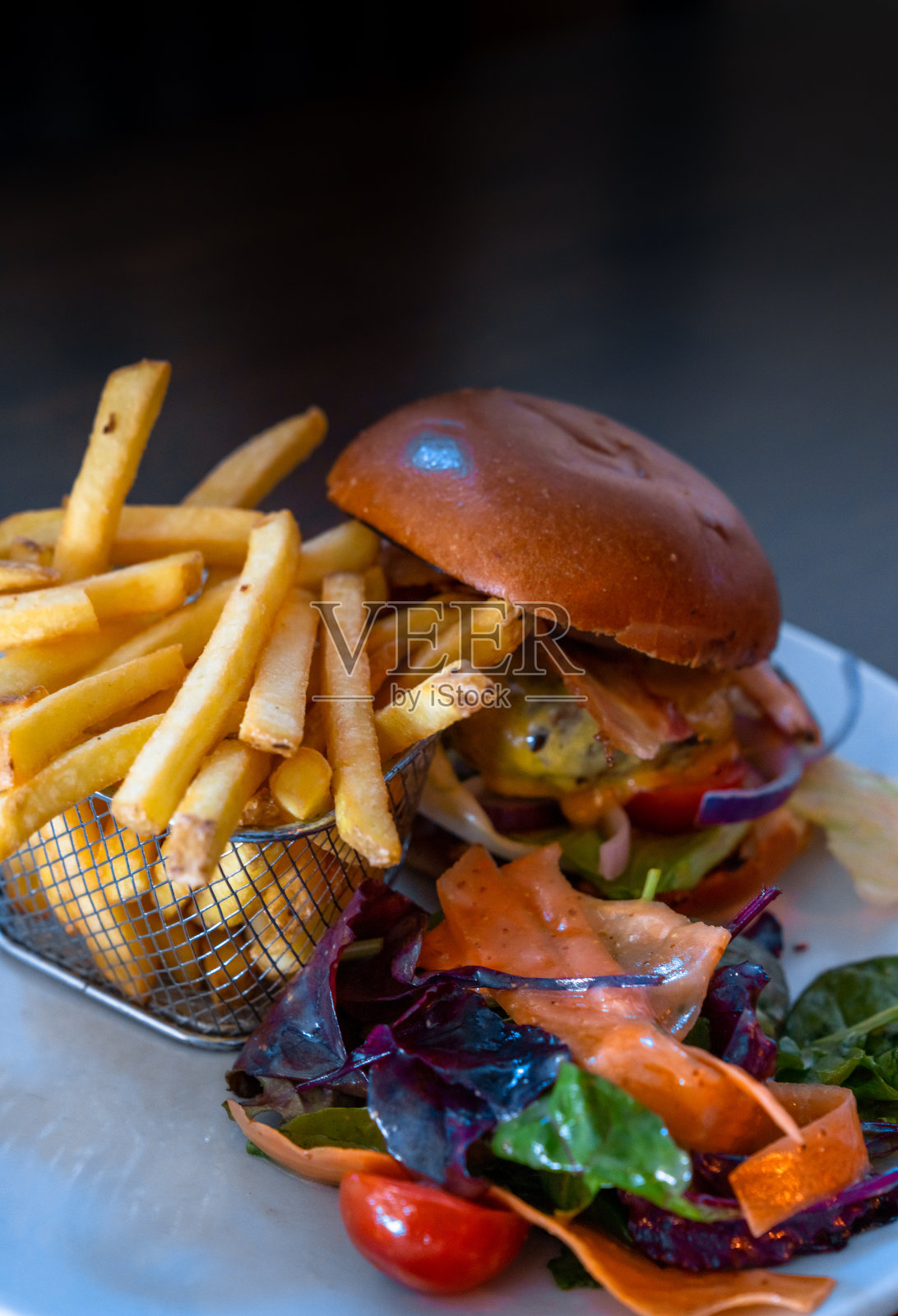 垂直视角的美味芝士汉堡和炸薯条在篮子与装饰新鲜蔬菜照片摄影图片