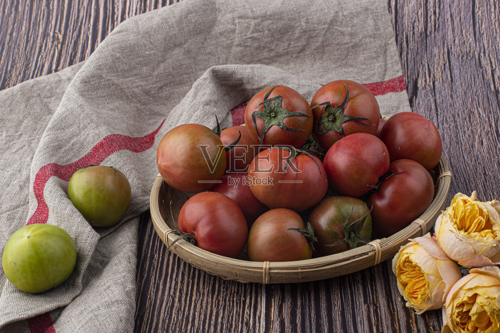 新鲜的红番茄在柳条篮子上灰色背景。照片摄影图片