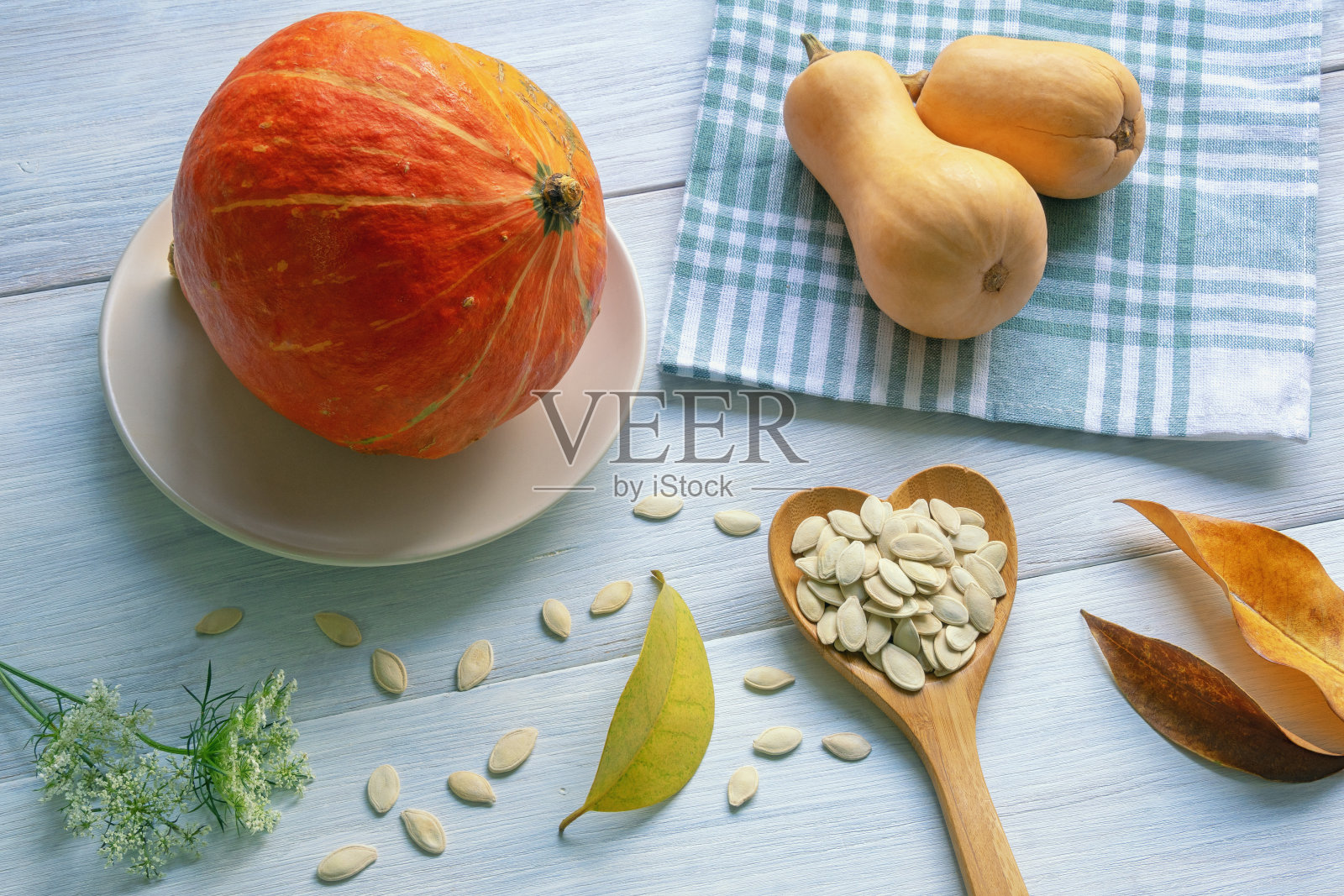 秋天。色彩斑斓的南瓜,秋叶和南瓜子放在质朴的桌子上照片摄影图片