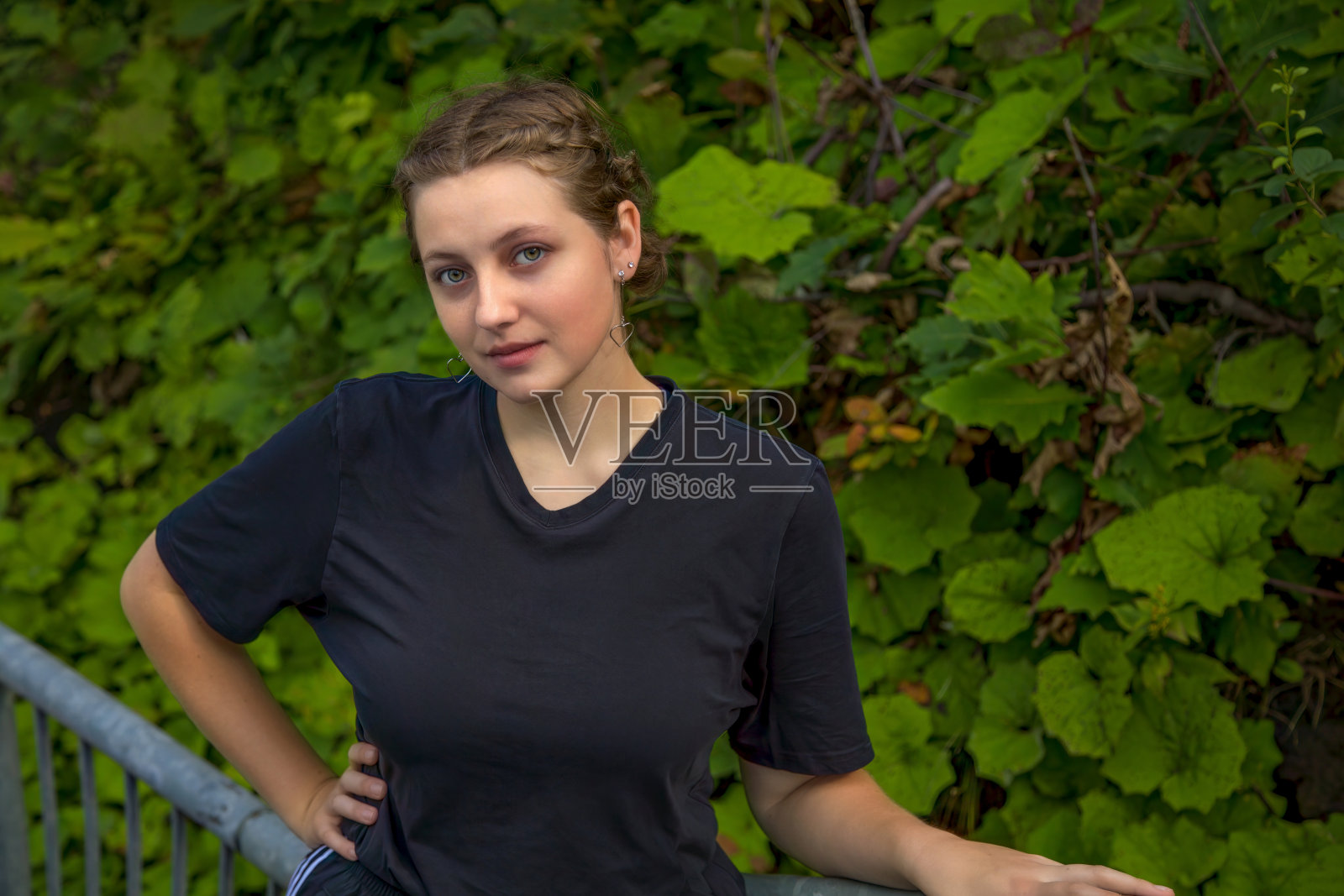 年轻女子在公园的绿色自然背景抱着金属栅栏照片摄影图片