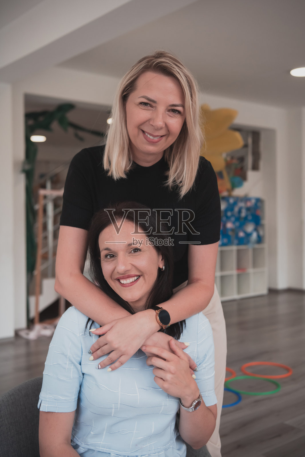 在幼儿园,教室的背景是两位拥抱的女教师的肖像照片摄影图片