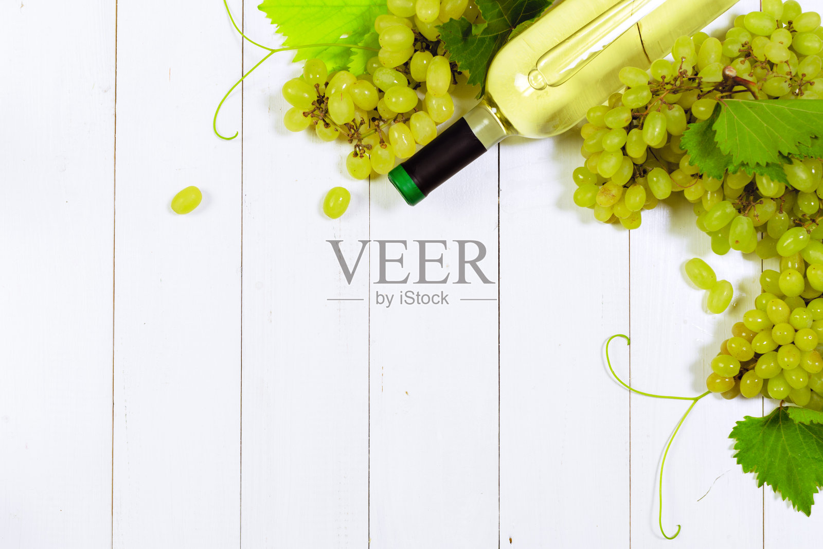 葡萄酒与白葡萄枝。在一张木桌上。照片摄影图片