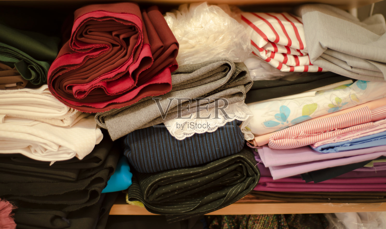 织物背景。架子上各种各样的纱线和织物。条纹和平原。红色和蓝色。缝纫厂。选择。缝纫和销售。照片摄影图片