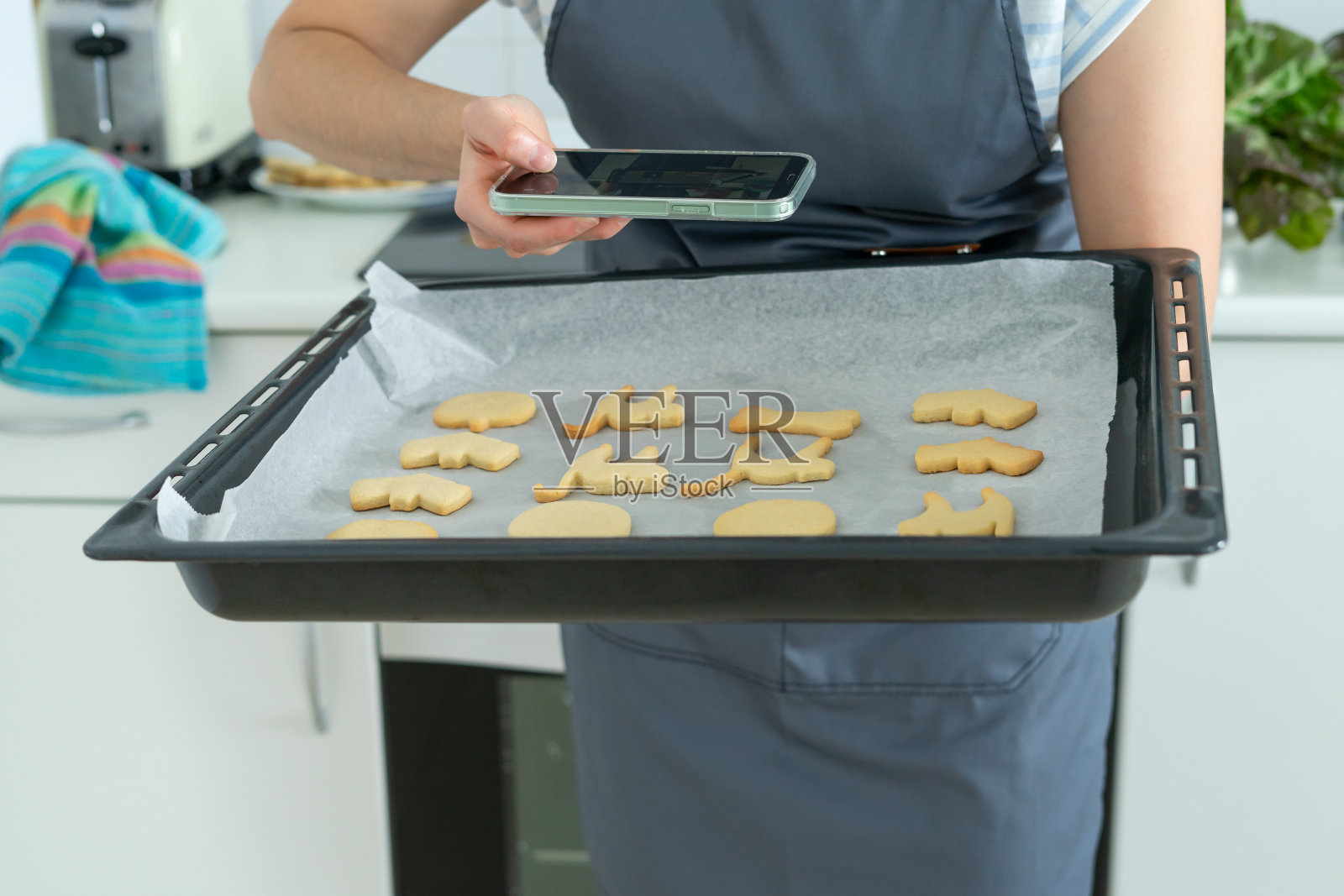 一名女子拿着托盘的万圣节饼干拍照。糕点店。副本的空间。照片摄影图片