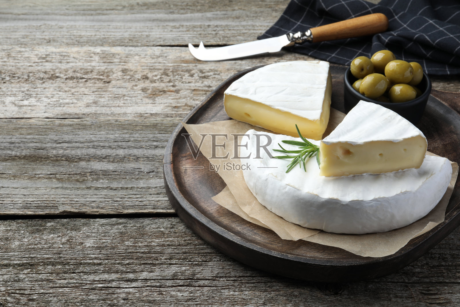 美味的切布里奶酪与迷迭香和橄榄放在木桌上,空间为文本照片摄影图片