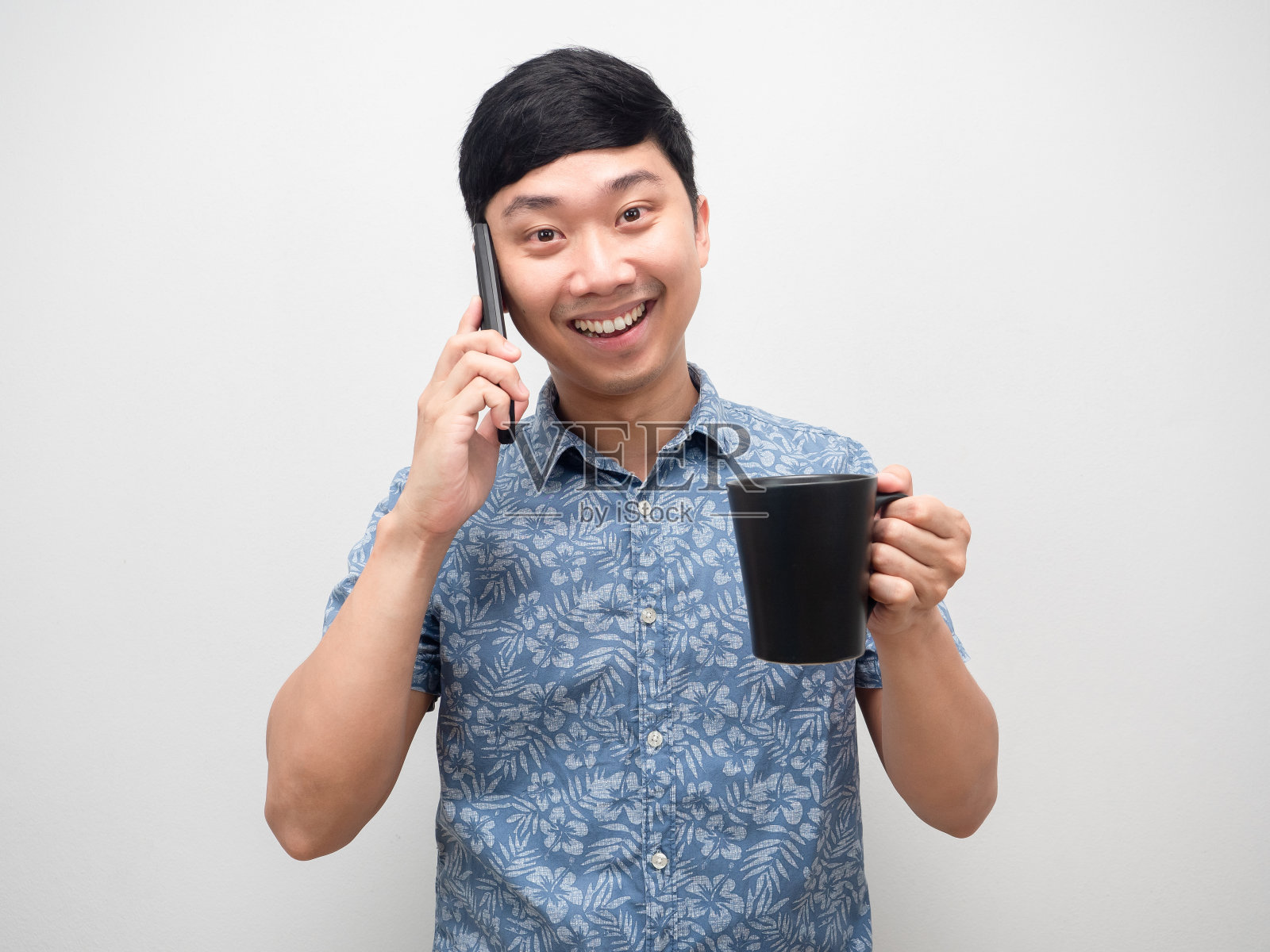潇洒的男人微笑著拿著咖啡杯,用手机交谈的画像照片摄影图片