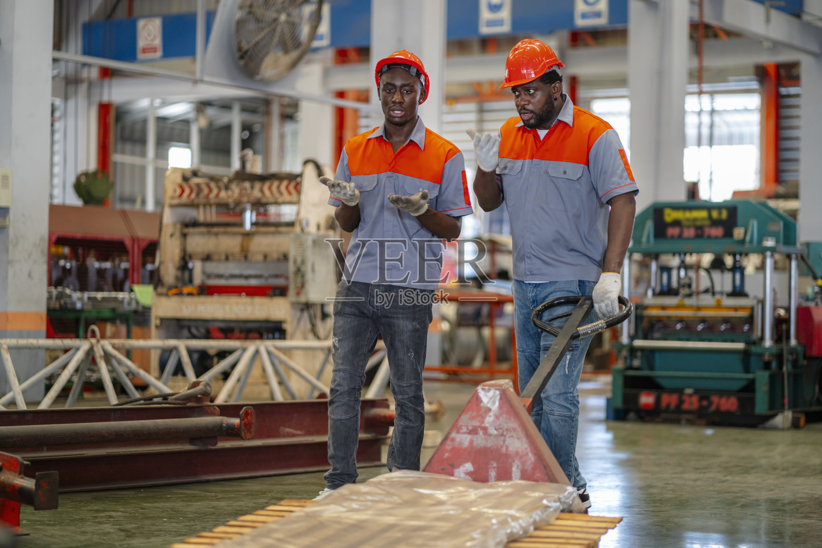 图为,生产线上的非洲裔男性工人正在工厂内拖着手推车前往配送中心为顾客服务。照片摄影图片